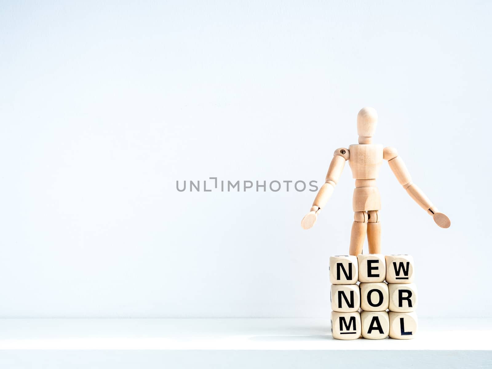 New Normal, words on wooden alphabet cube and wooden figure on white background with copy space. New normal life after covid-19 pandemic concept.