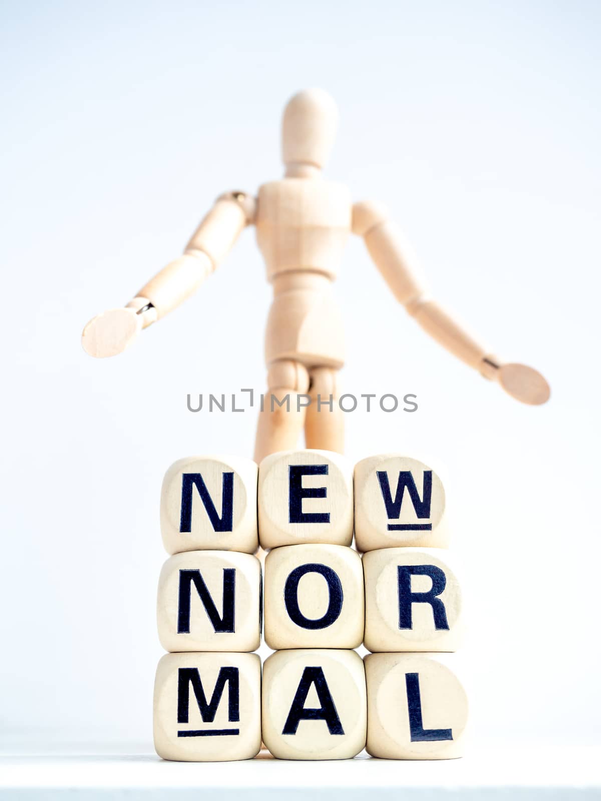 Close-up New Normal, words on wooden alphabet cube and wooden figure on white background, vertical style. New normal life after covid-19 pandemic concept.