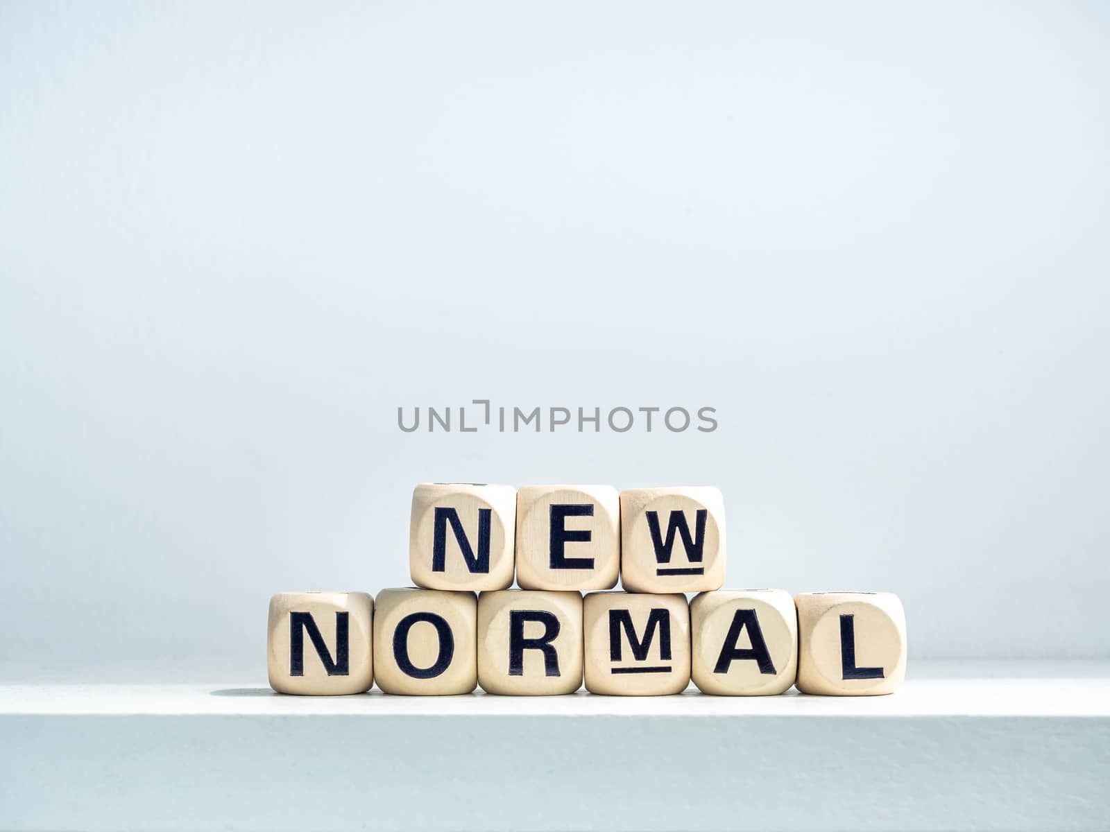 Close-up New Normal, words on wooden alphabet cube on shelf on white background. New normal after covid-19 pandemic concept.