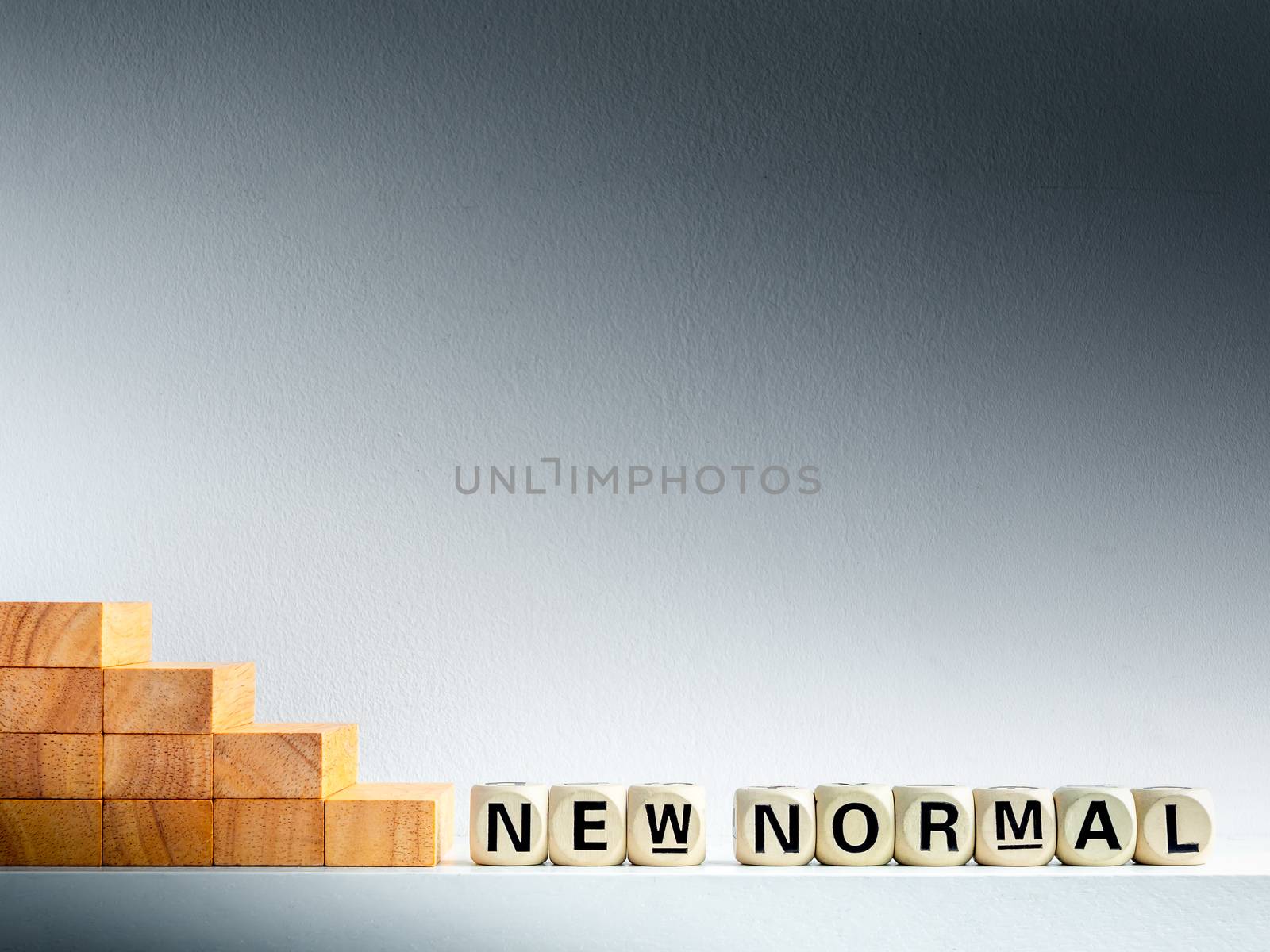 Stairs down to New Normal, words on wooden alphabet cube on dark background with copy space. New normal after covid-19 pandemic concept.