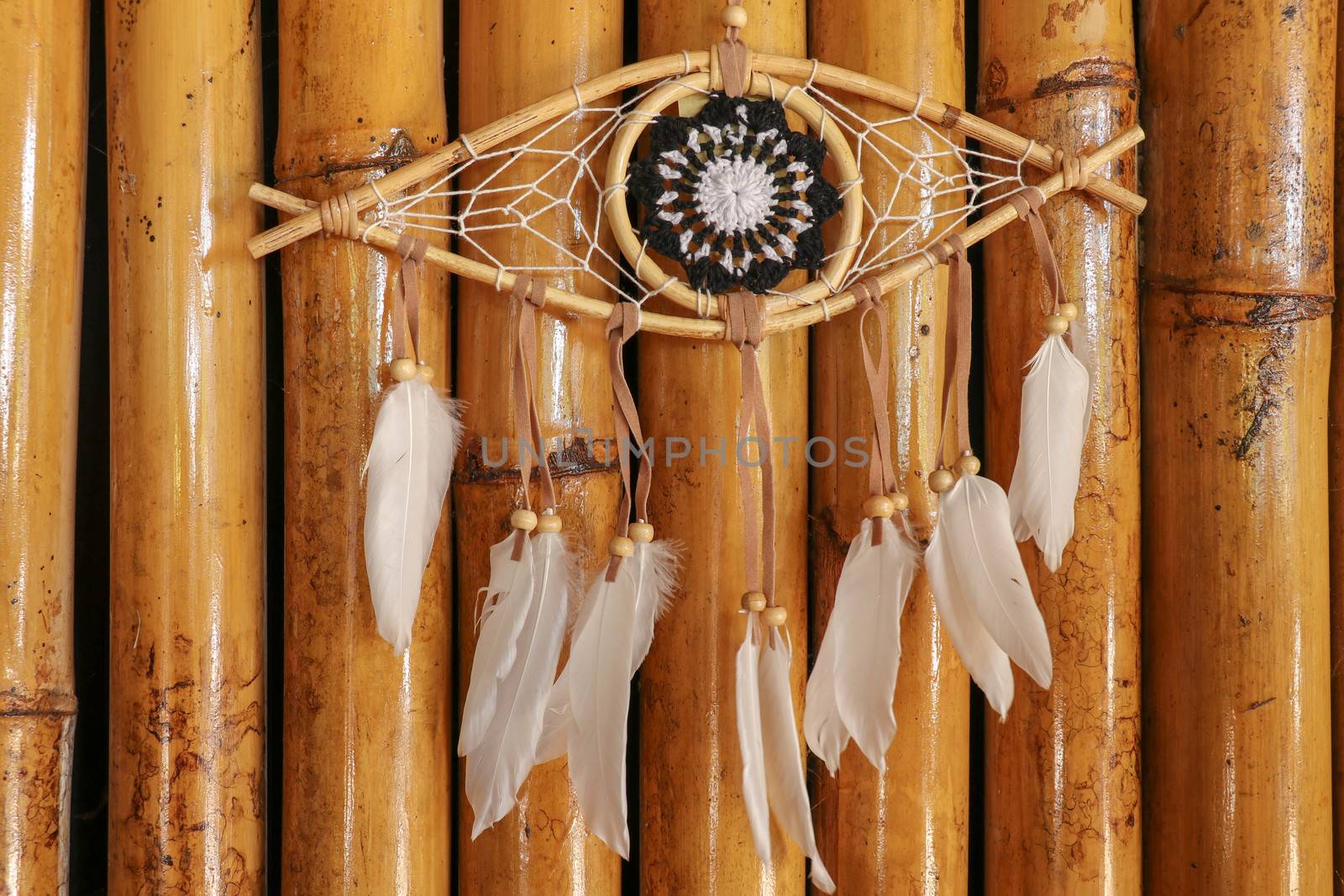 god eye of providence dreamcatcher with white feathers on a wodden background.