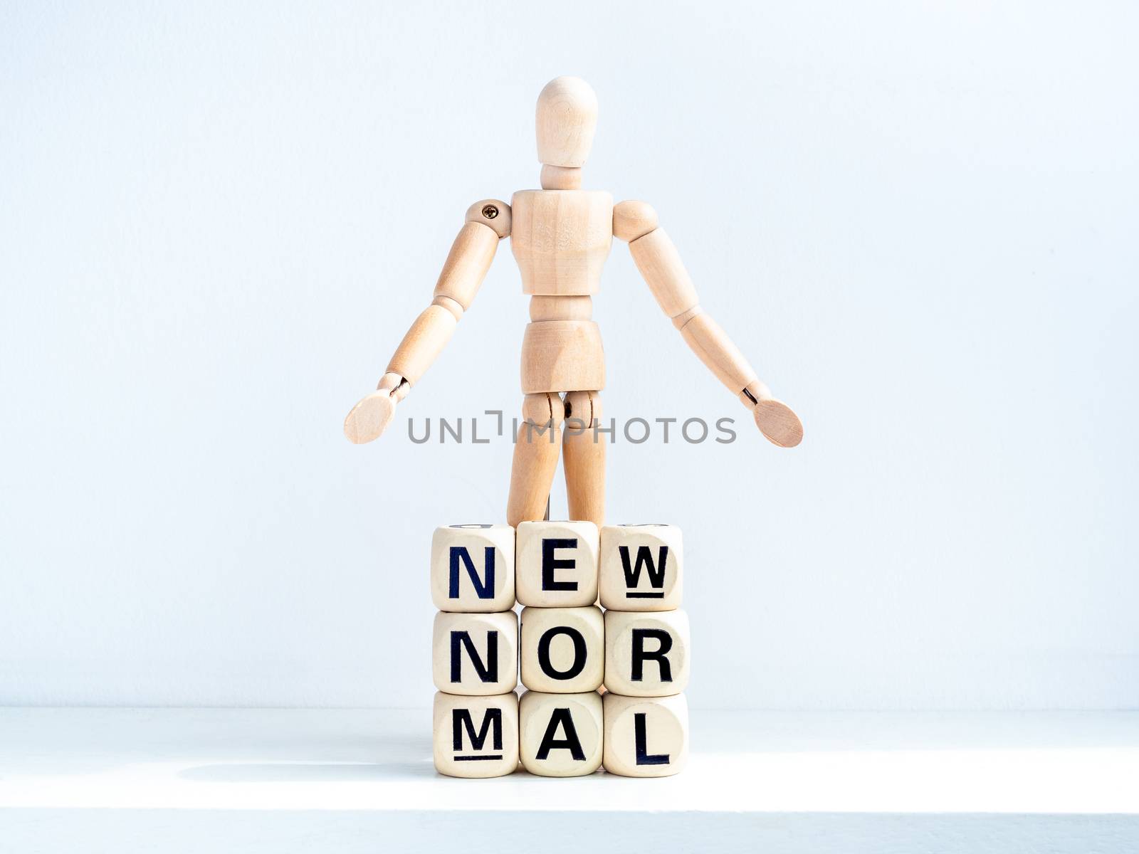 New Normal, words on wooden alphabet cube and wooden figure on white background. New normal life after covid-19 pandemic concept.