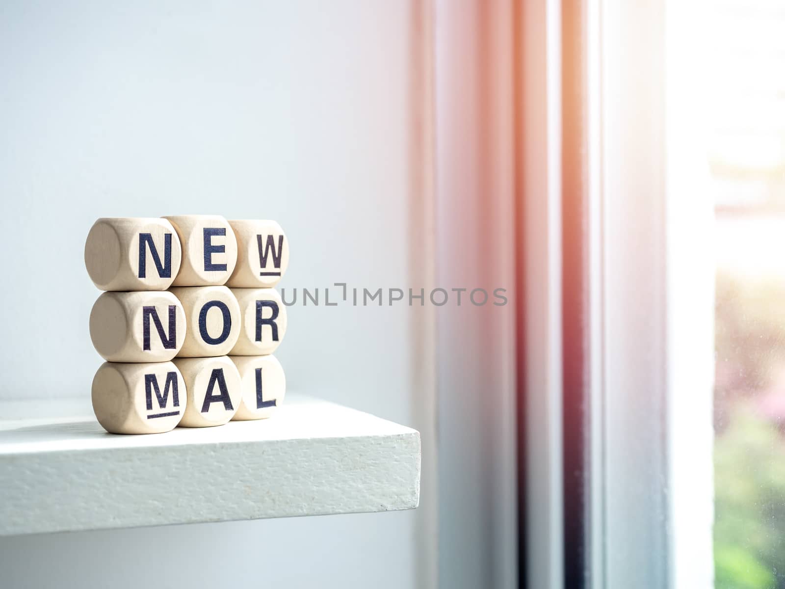 Close-up New Normal, words on wooden alphabet cube on shelf near window with sunlight. New normal after covid-19 pandemic concept.