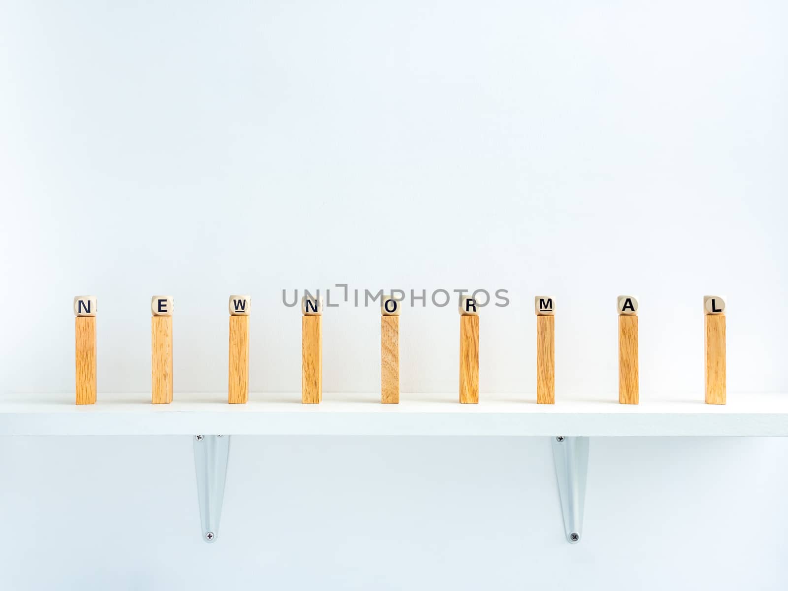 New normal and social distancing concept. New Normal, words on wooden alphabet cube on row of wooden dominoes with distance space on shelf on white background.