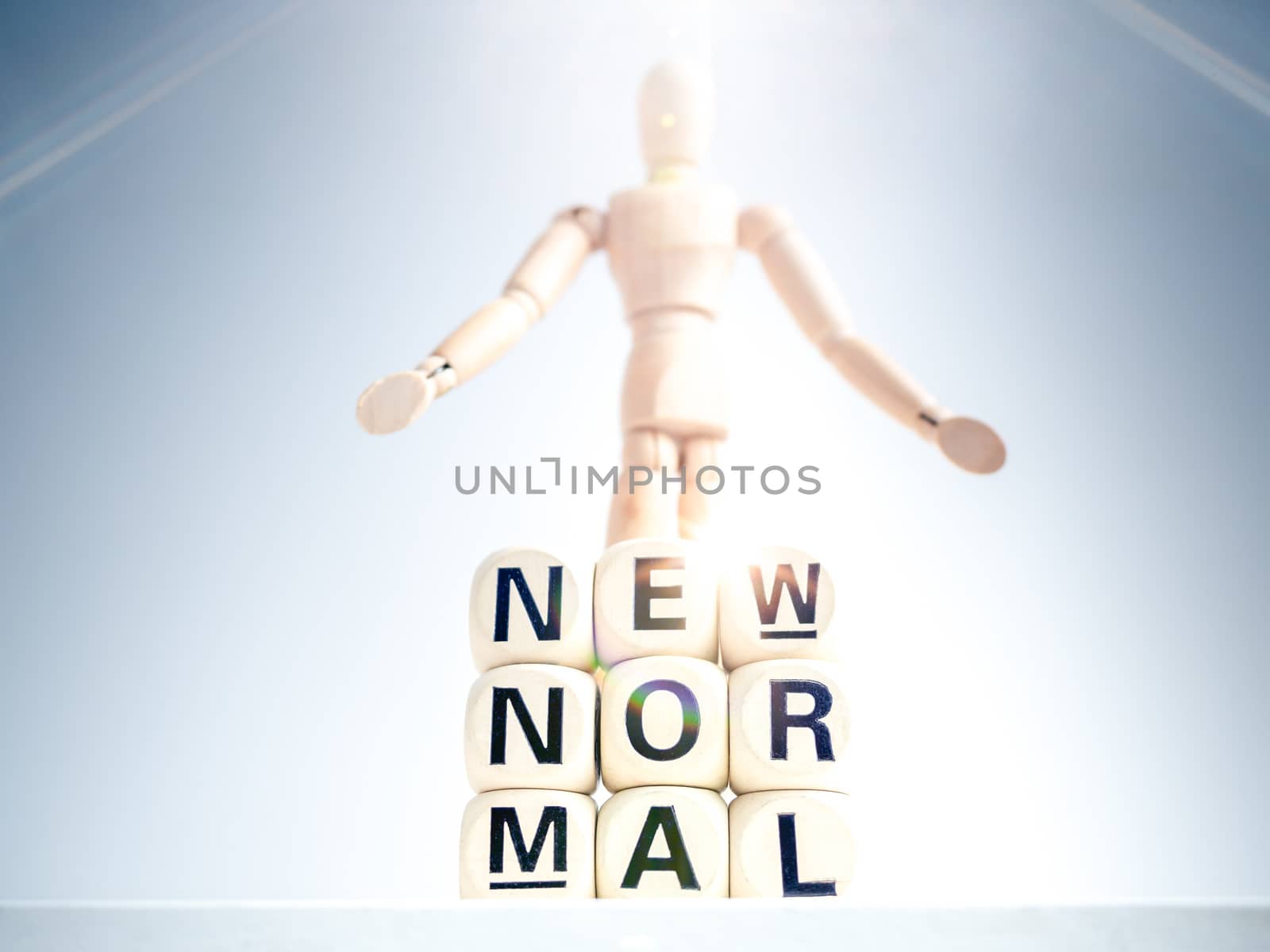 New Normal, words on wooden alphabet cube and wooden figure on white background with sparkle light. New normal life after covid-19 pandemic concept.