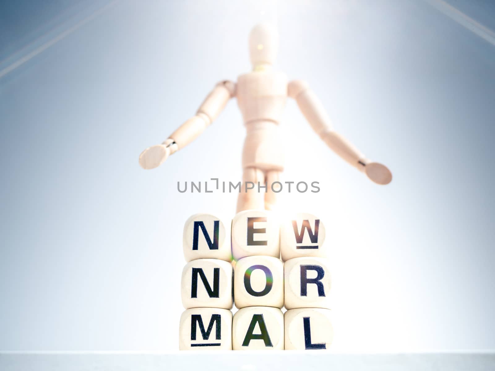 New Normal, words on wooden alphabet cube and wooden figure on white background with sparkle light. New normal life after covid-19 pandemic concept.