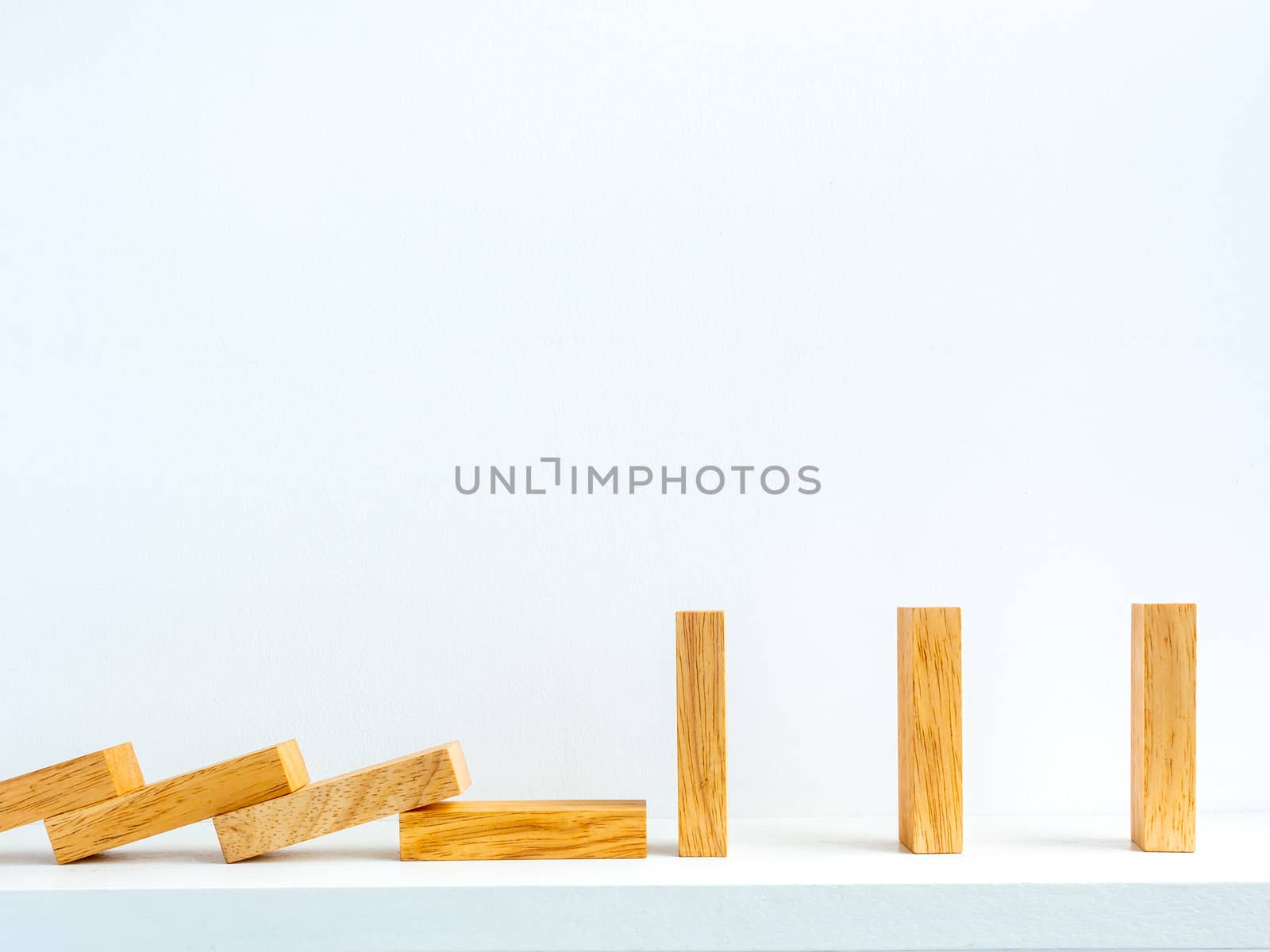 Social Distancing concept. Row of falling and standing wooden dominoes with distance space on shelf on white background with copy space.