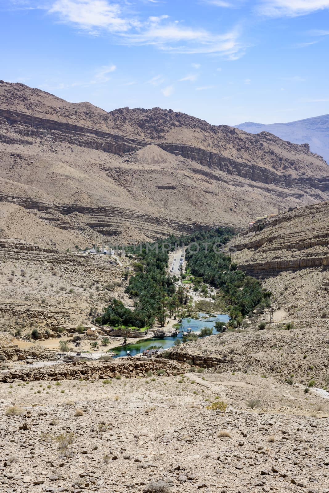 Top view of Wadi Bani Khalid, Sultanate of Oman. We can see the main pool and many tourists going and coming in/from the canyon. This is one of the most visited wadi in Oman with easy access. Many travel agencies are stopping by. It is a main destination.