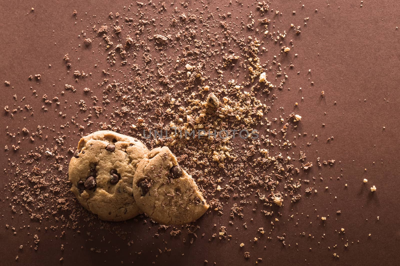 Broken chocolate chip cookies on brown background. Top view. Copy space.