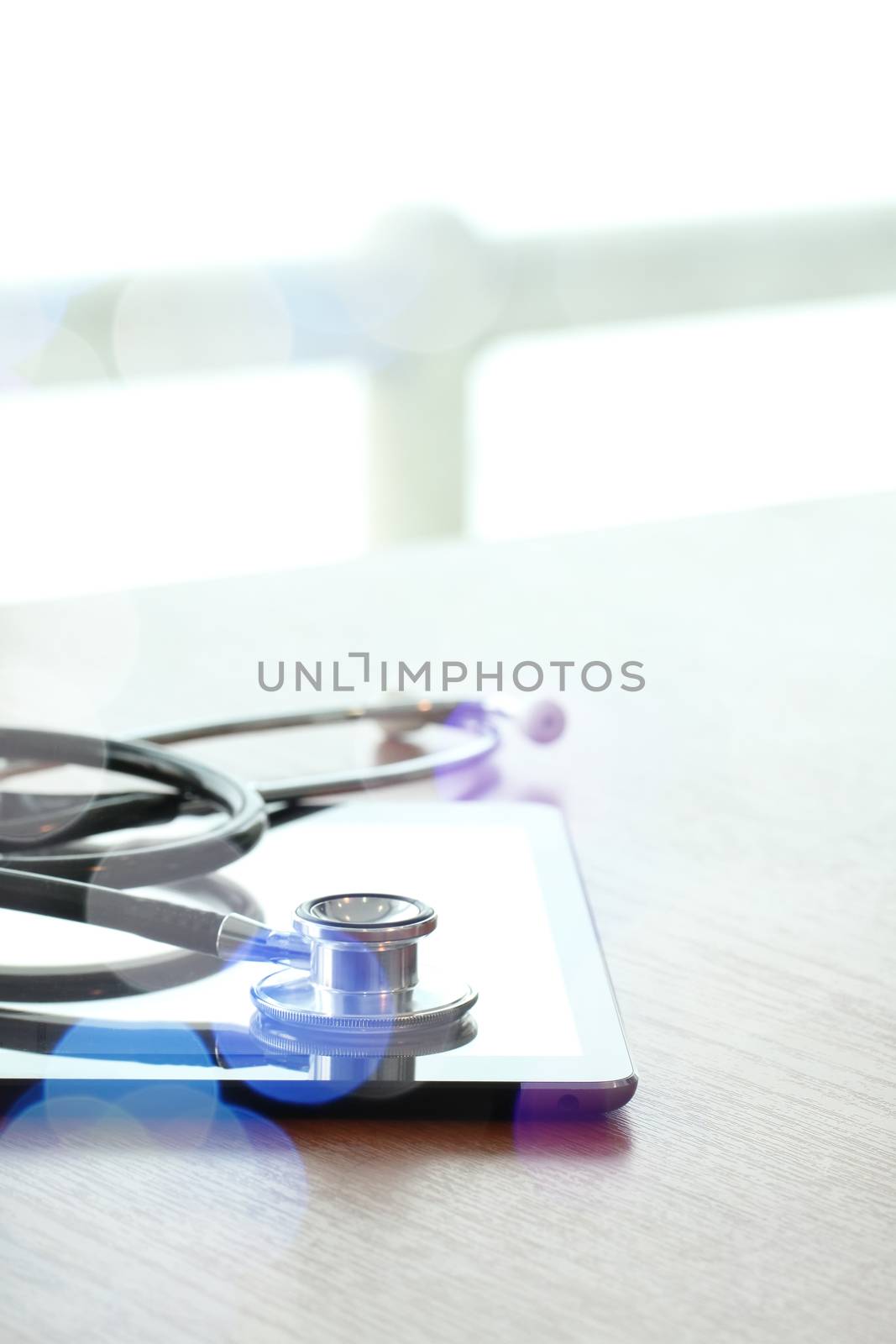 Studio macro of a stethoscope and digital tablet with shallow DOF evenly matched abstract on wood table background copy space