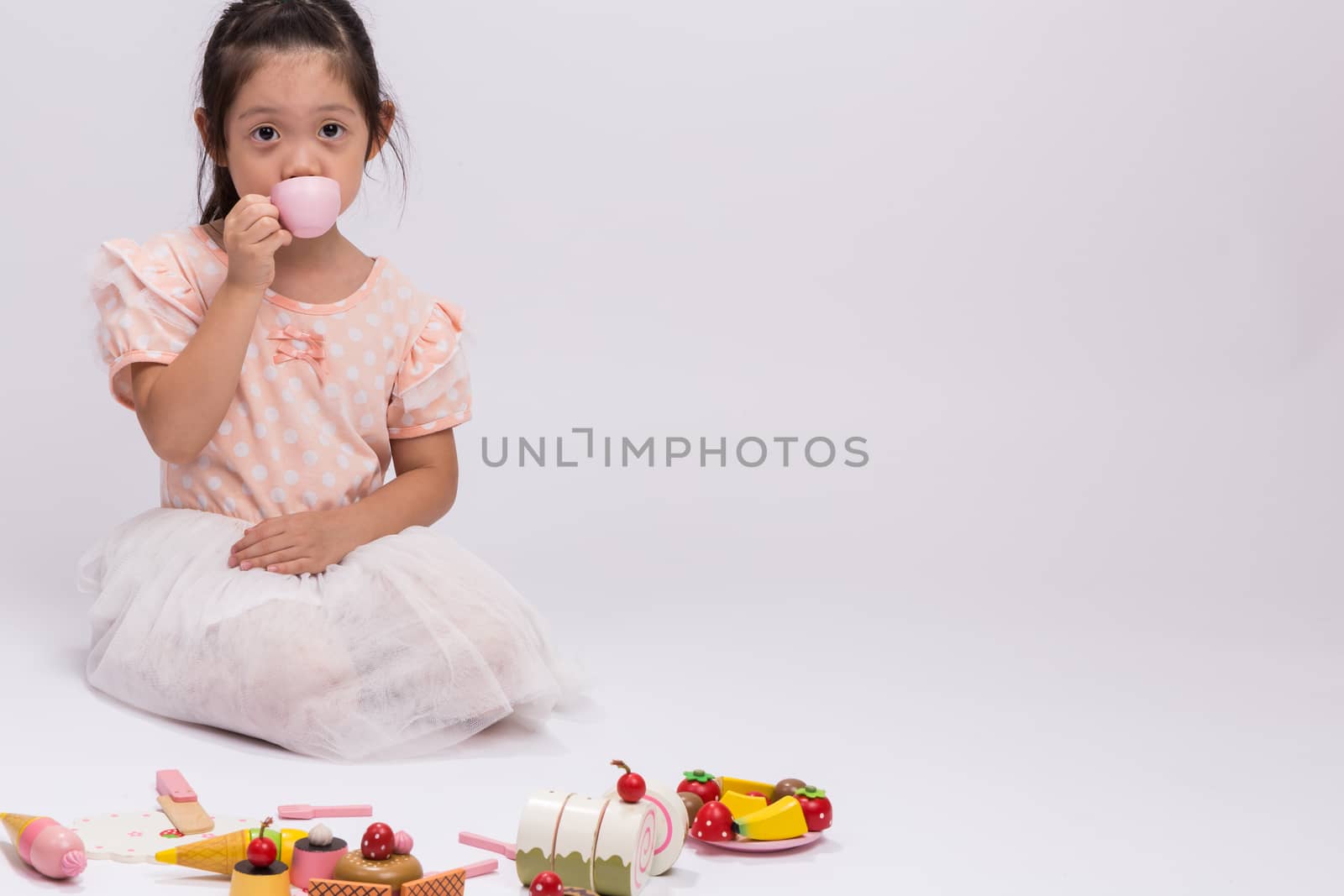 Happy little girl is playing with her cooking toy set.