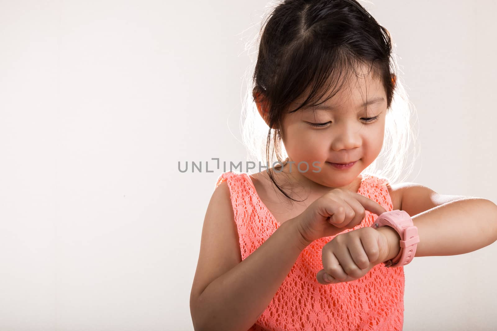 Little girl is using smartwatch on her wrist background.
