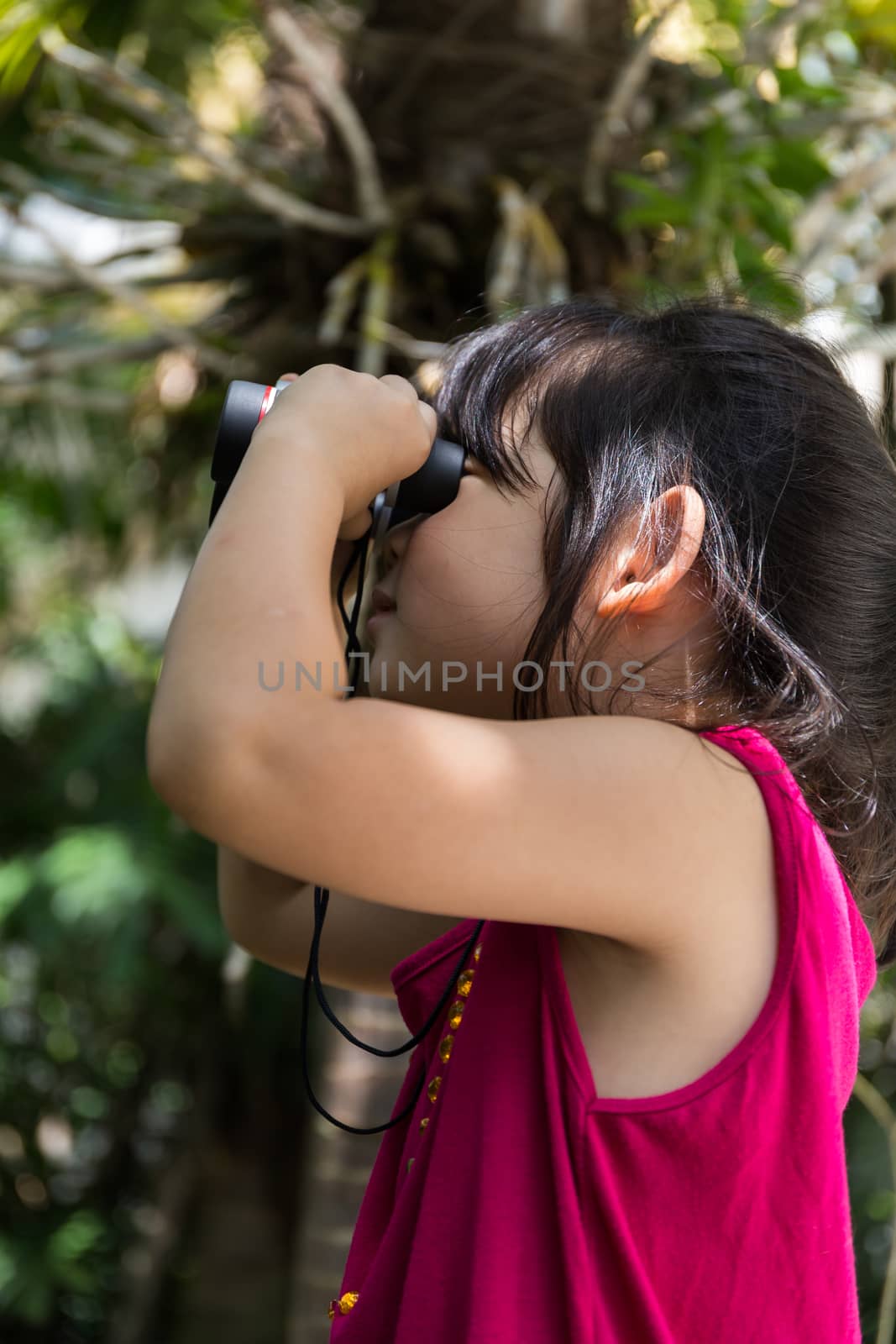 Cute girl is looking through binoculars during a trip.