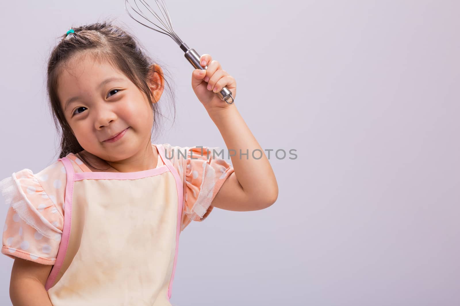 Happy little girl holding kitchenware in her hands.