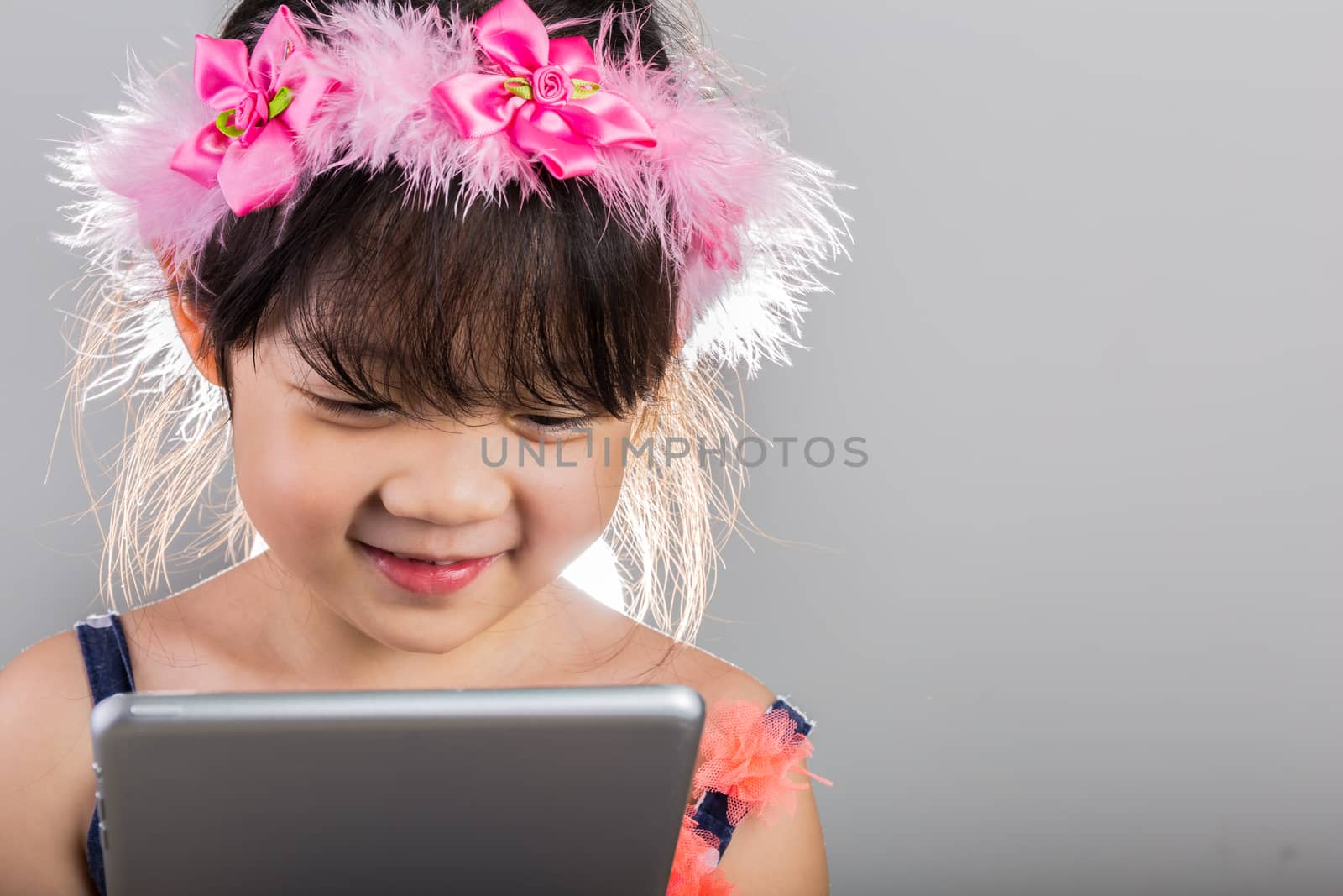 Asian child is using tablet.