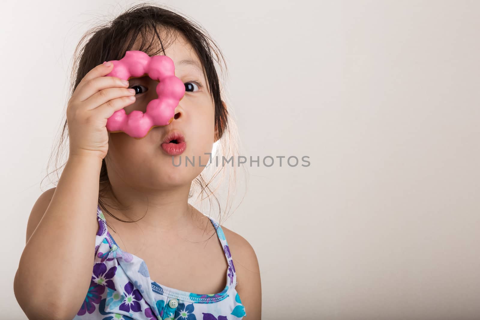 Little girl is looking through imaginary glasses from a donut.