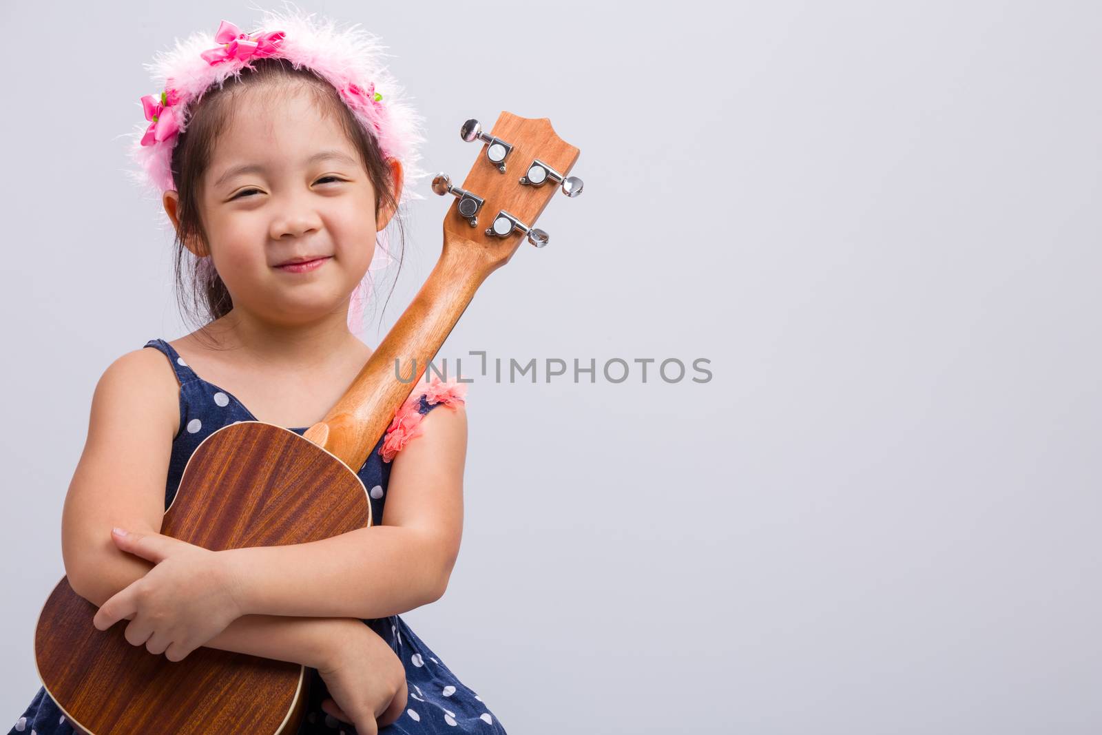 Little girl with her ukulele, string music instrument.