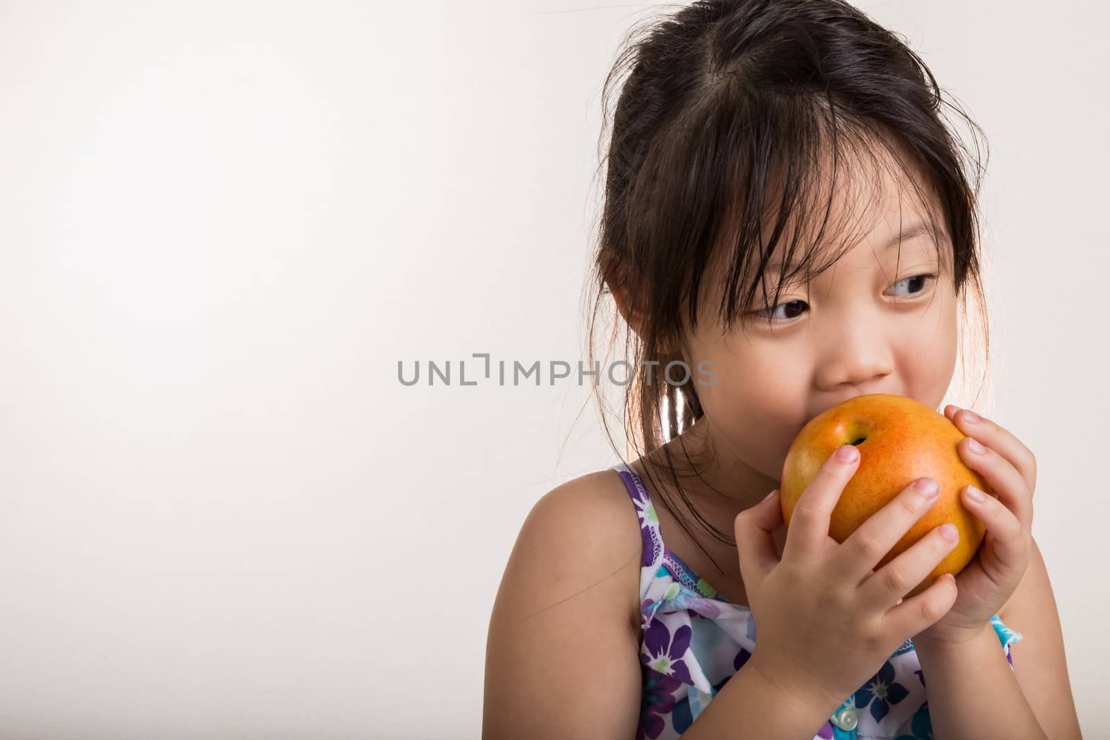 Little girl takes a bite of apple in her hands.