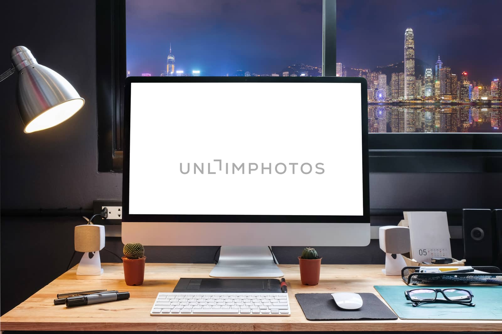 Graphic designer's workspace with city night view with a pen tablet, a computer and white background for text