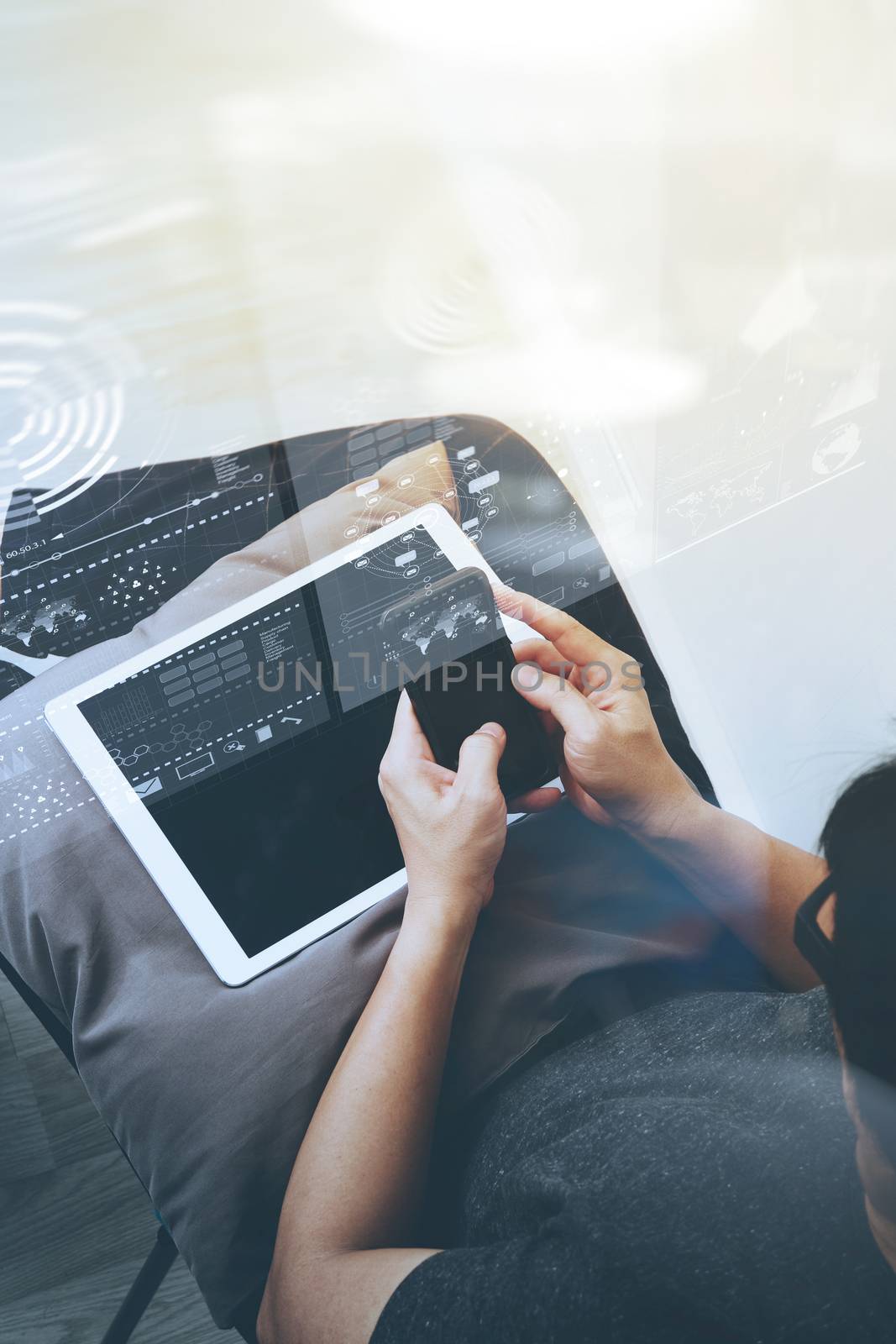 top view of hipster hands using smart phone and digital tablet pro with business strategy diagram layer while sitting on a cosy sofa in his home as concept