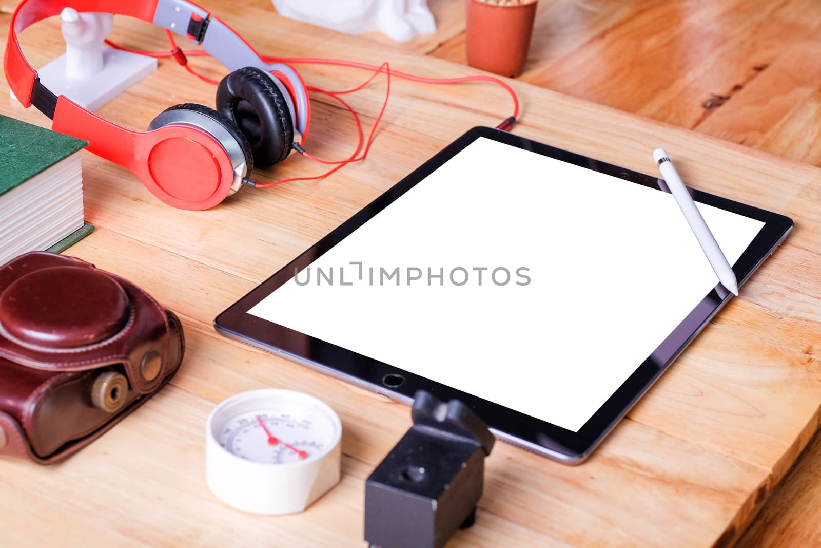 Office workplace with tablet and headphone on wood table.