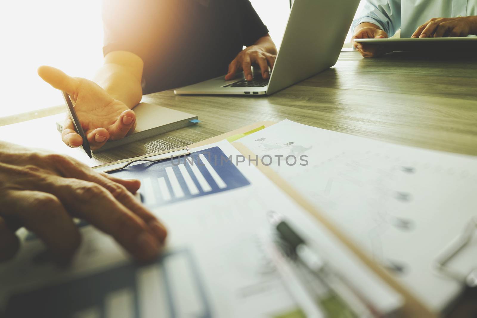 three colleagues interior designer discussing data and digital tablet and computer laptop with business document  on wooden desk as concept                           