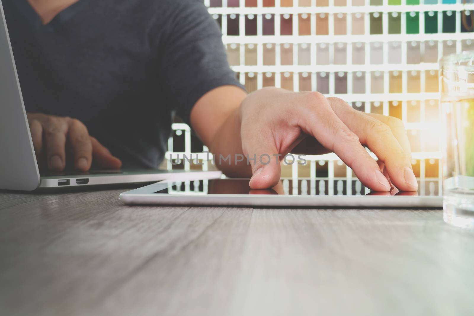 interior designer hand working with digital tablet and laptop computer and sample material on wooden desk as concept