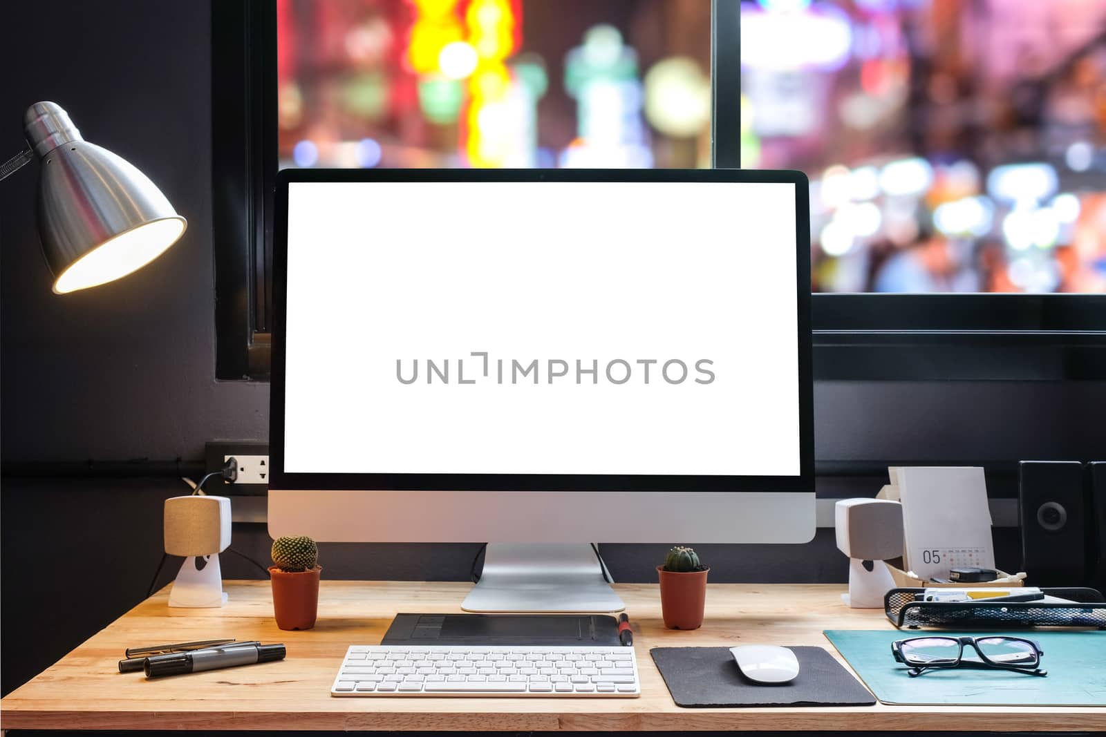 Graphic designer's workspace with city night view with a pen tablet, a computer and white background for text