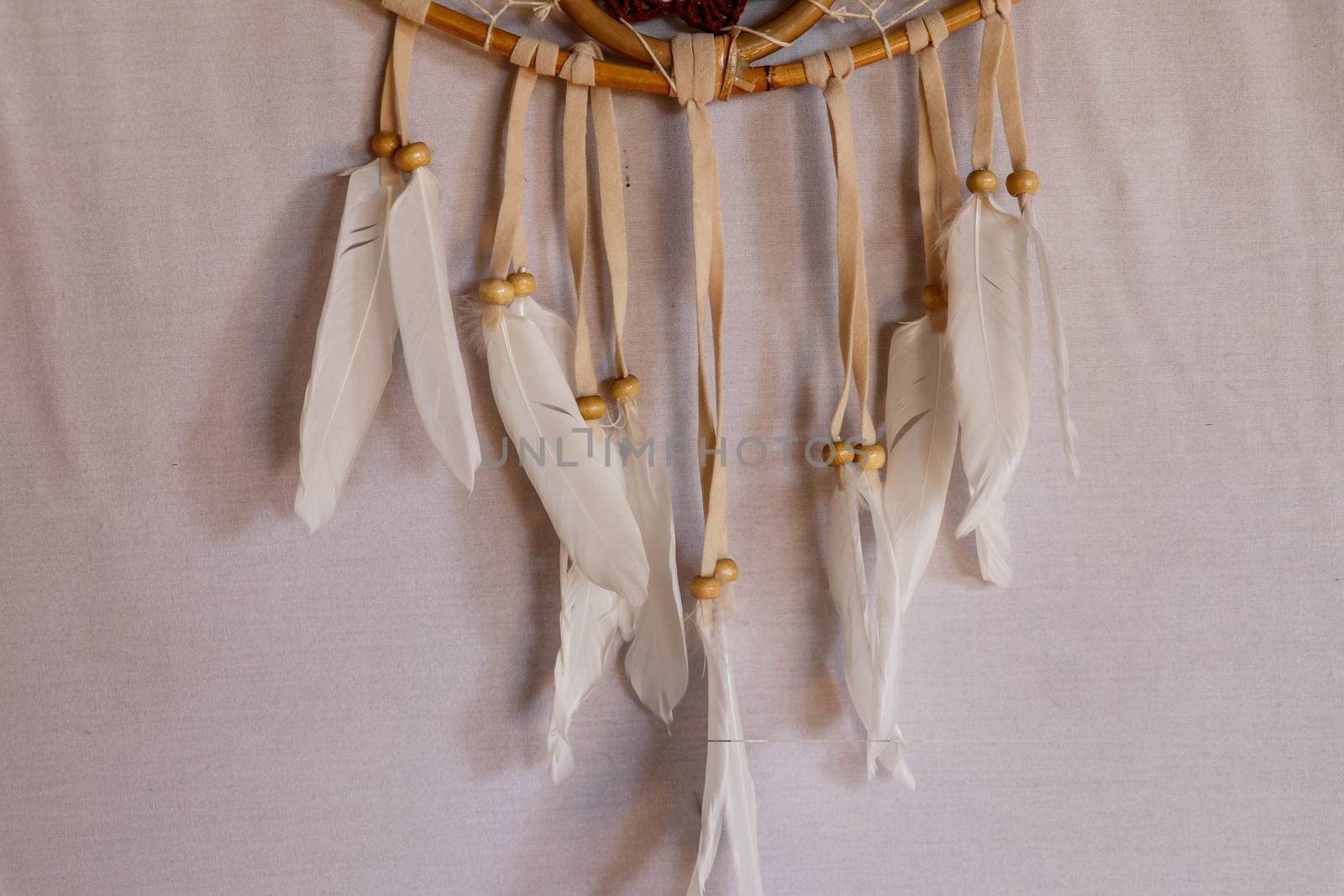 Closeup of white dream catcher a small white hoop decorated with feathers and beads.