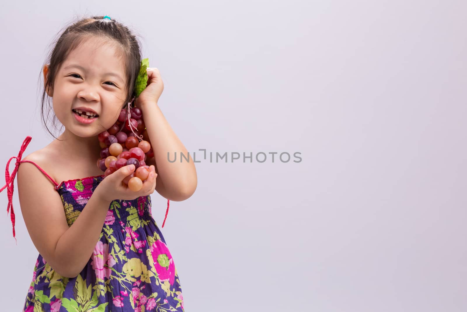 Child is holding grapes in her hand background.