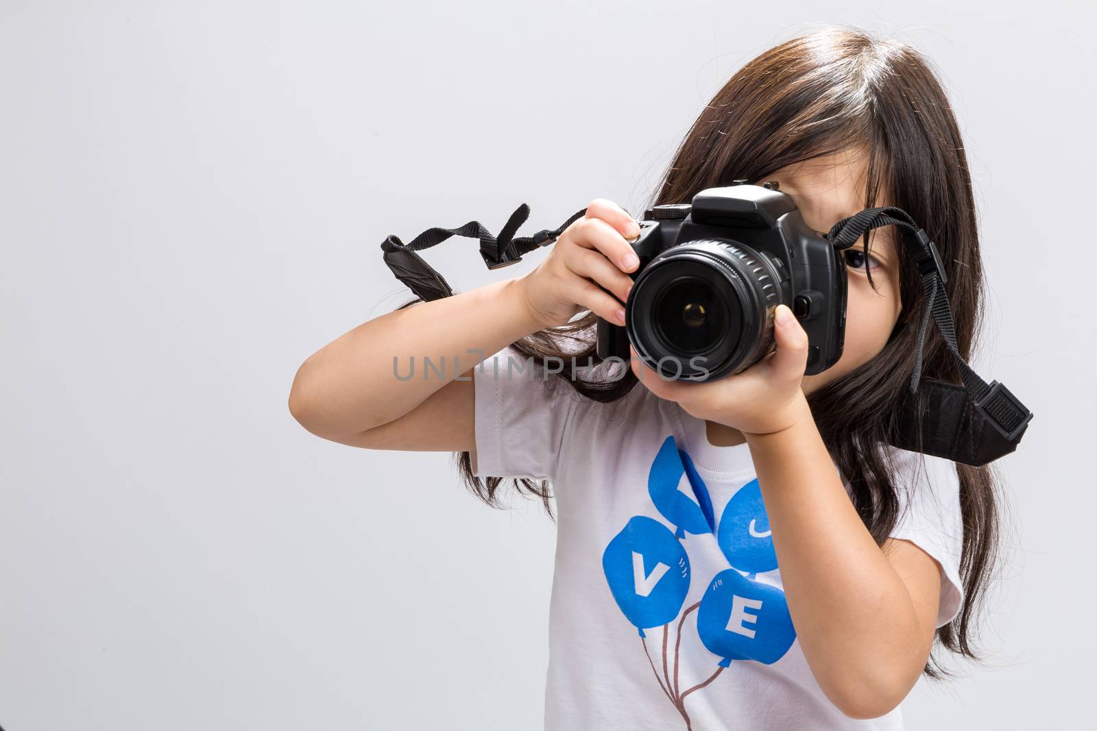 Little kid using DSLR camera to take some photos in studio.