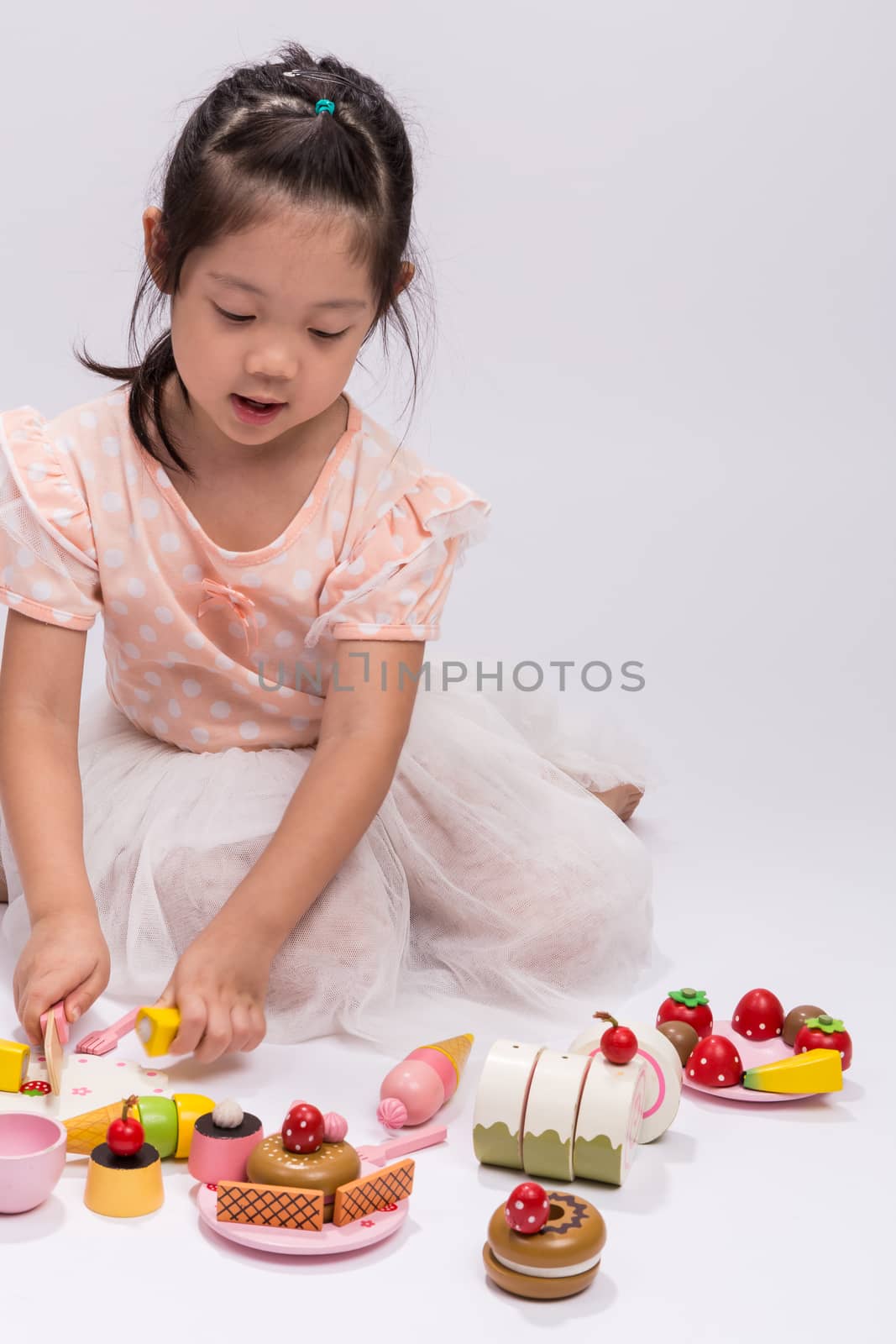 Happy little girl is playing with her cooking toy set.