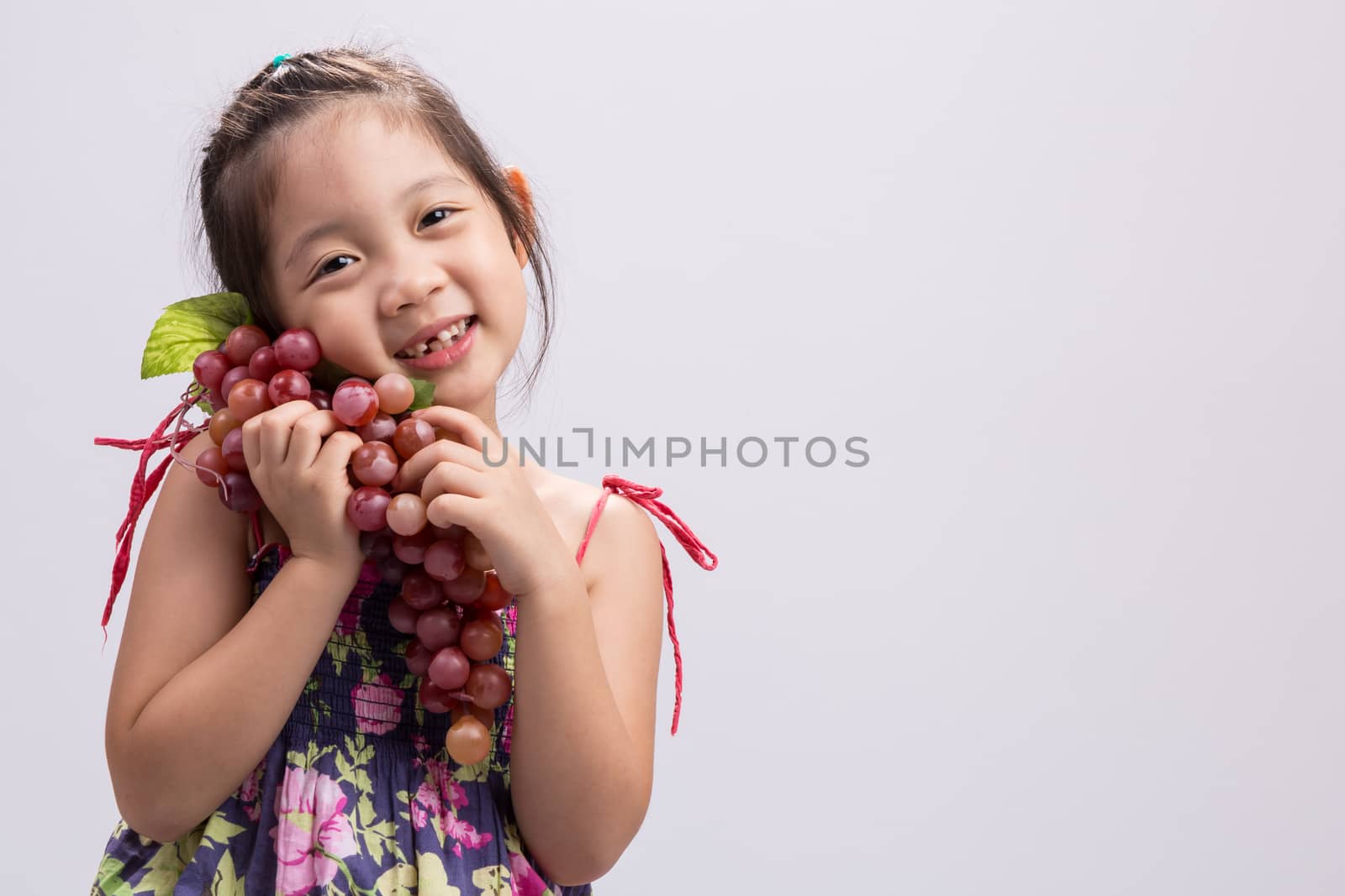 Child is holding grapes in her hand background.