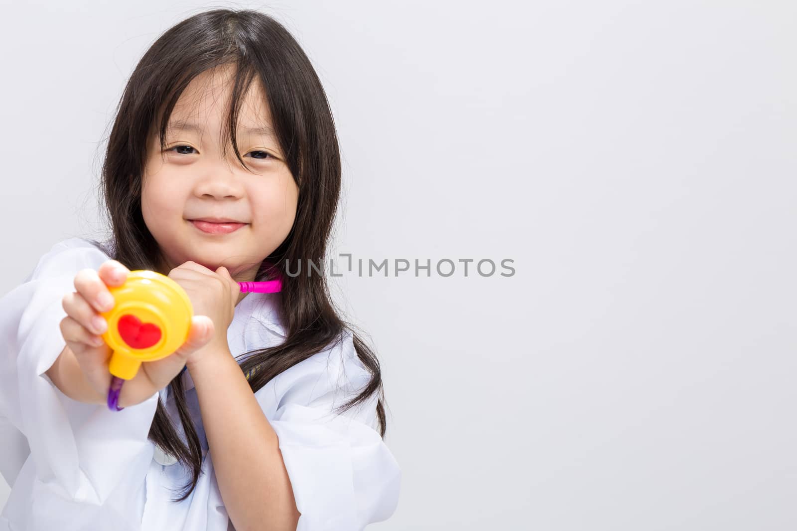 Young little girl dressing doctor with medical instrument in hands.
