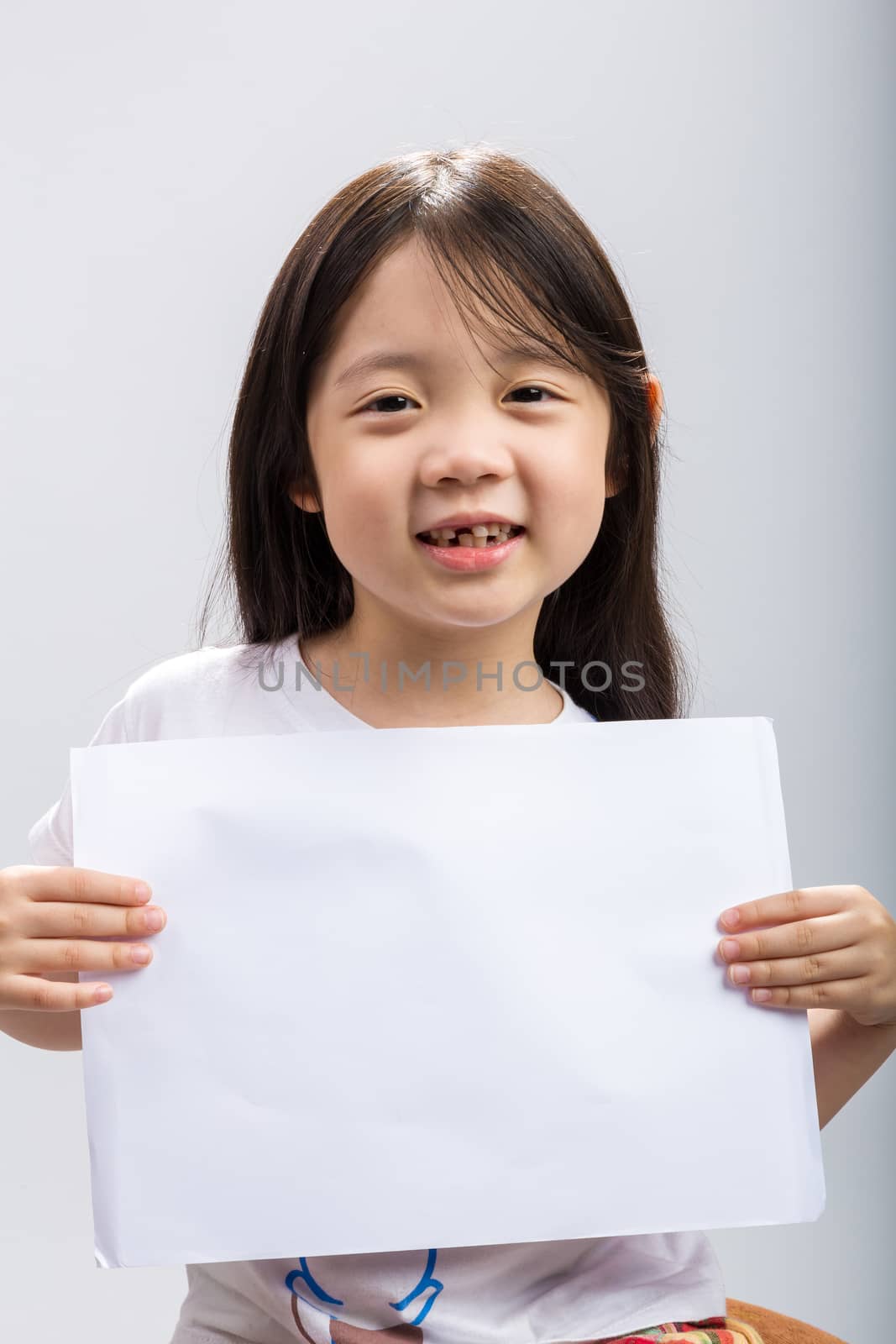 Studio isolated kid holding white sheet of blank paper.