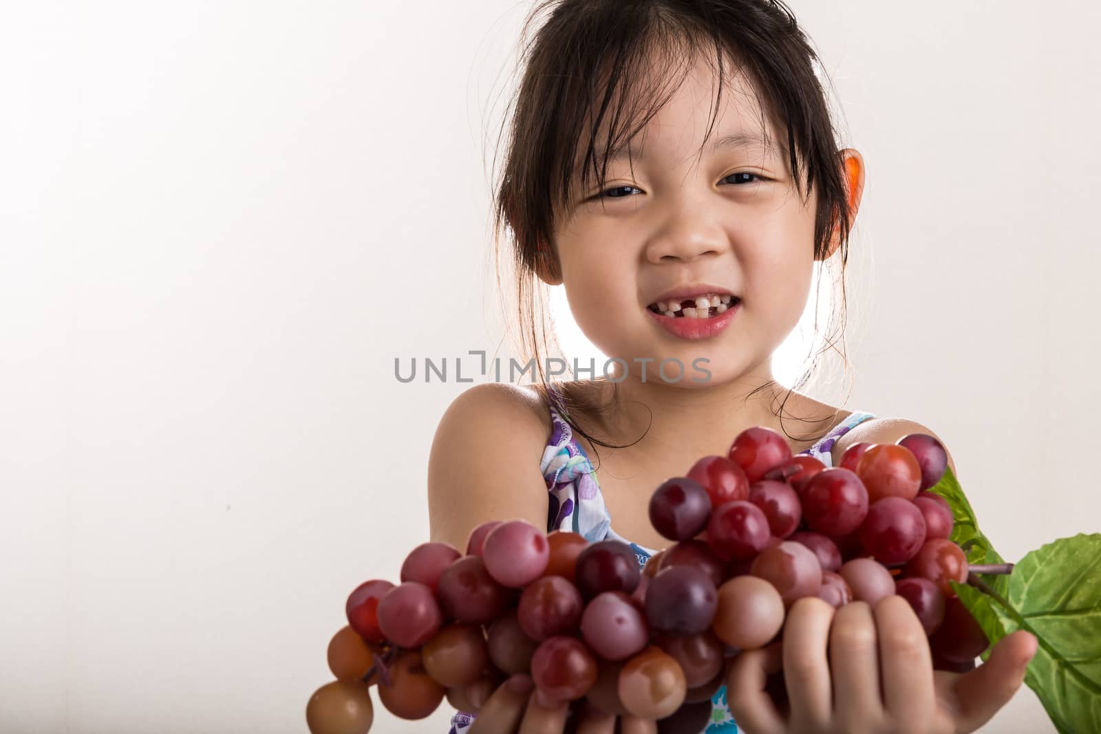 Child is holding grapes in her hands background.