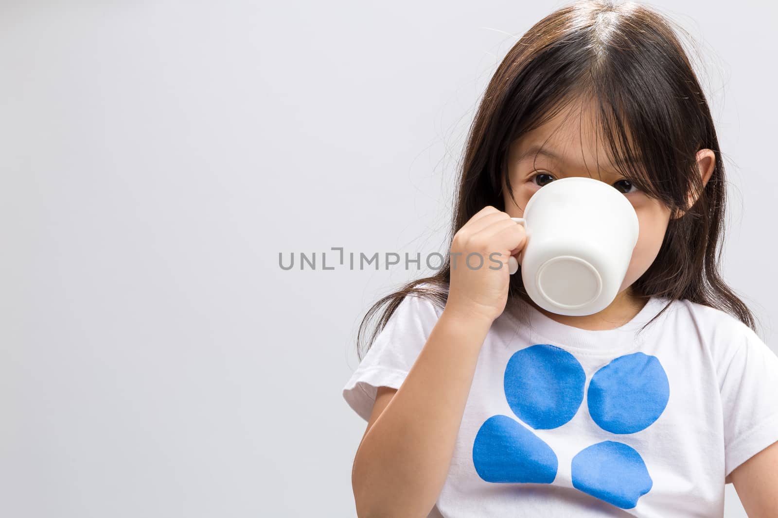 Kid drinking milk on studio isolated white background.