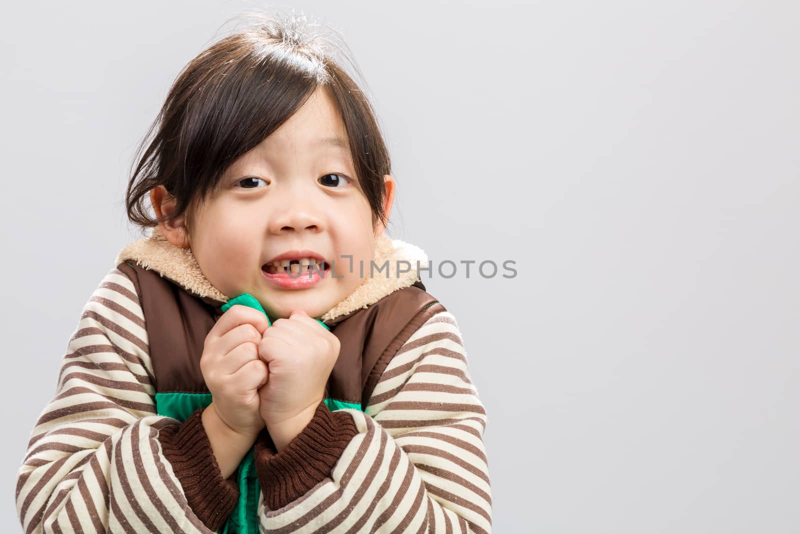 Cute Asian girl shivering in coat, studio isolated white background.