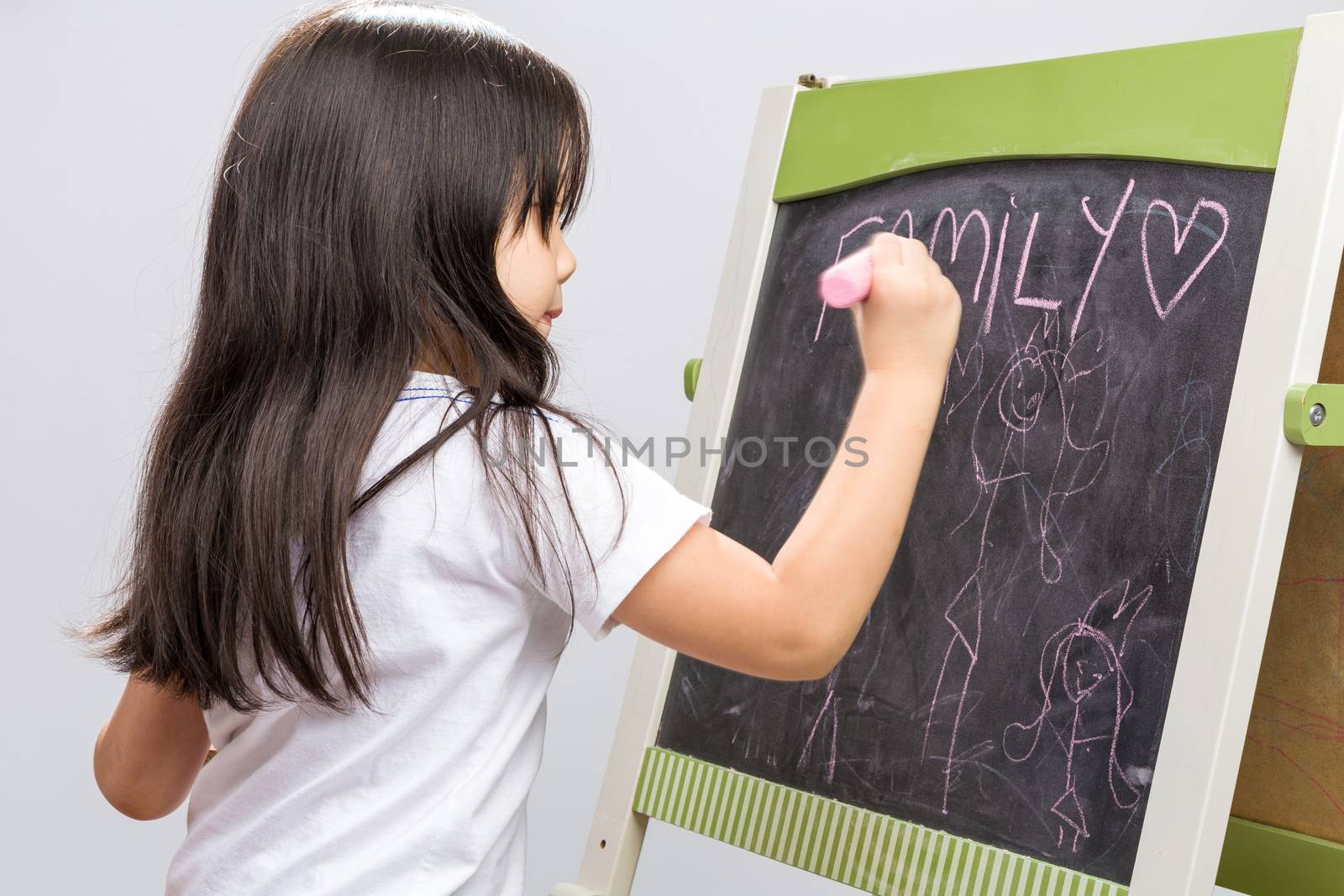 Little kid writing something on blackboard studio isolated.