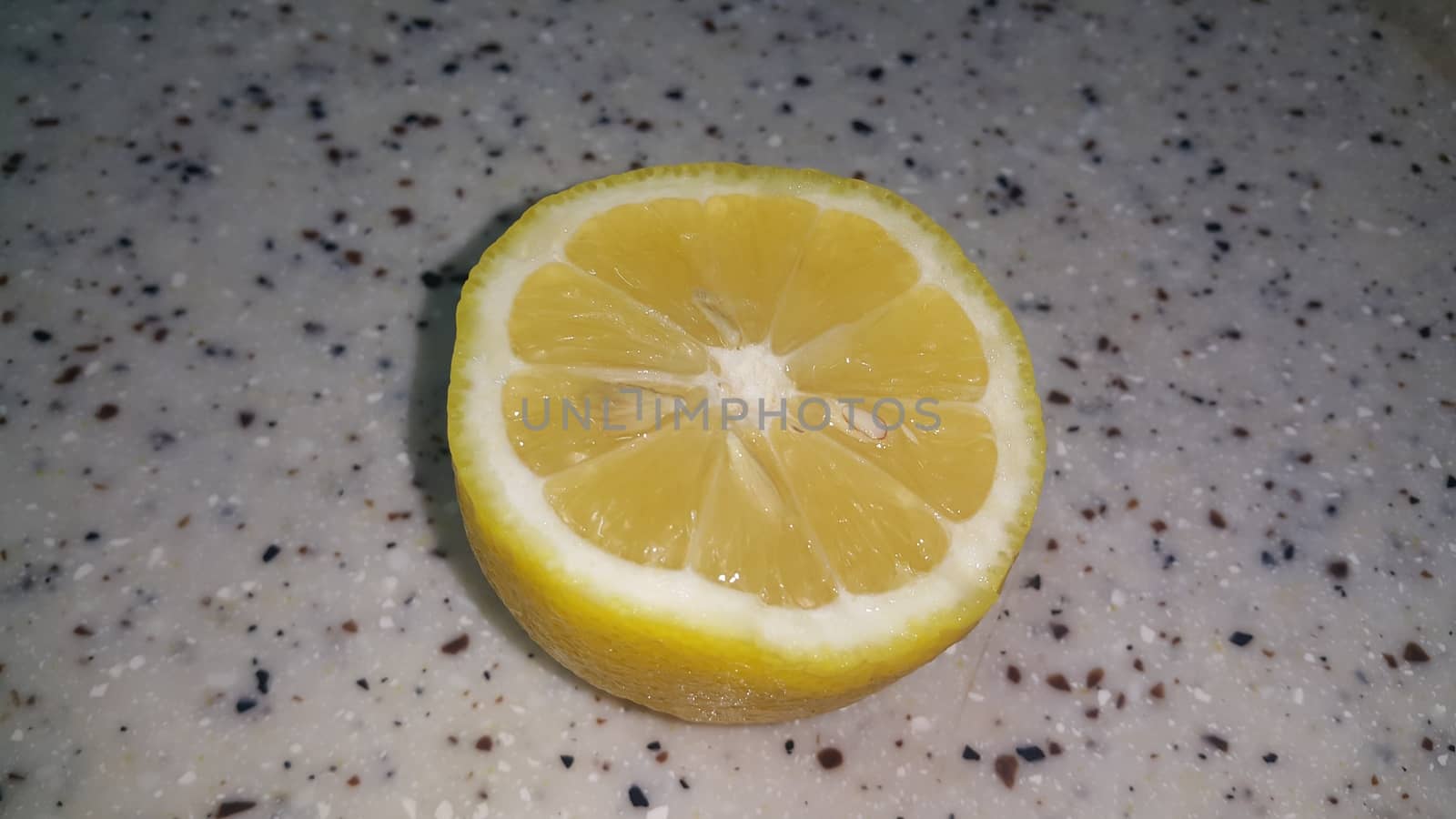 Fresh lemon slices with yellow peelings placed on a grey floor by Photochowk