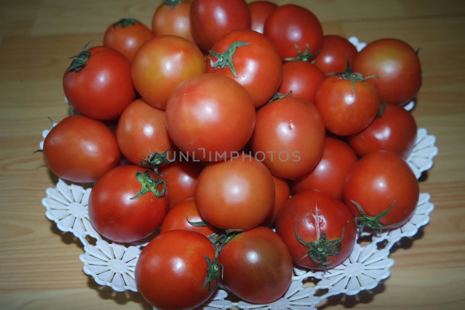 Close-up view of red tomatoes in white basket on a wooden floor in market for sale. A fruit background for text and advertisements