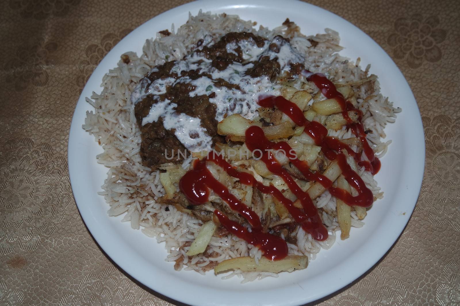 Delicious traditional dish of rice, potato fries and cereals with red ketchup. by Photochowk