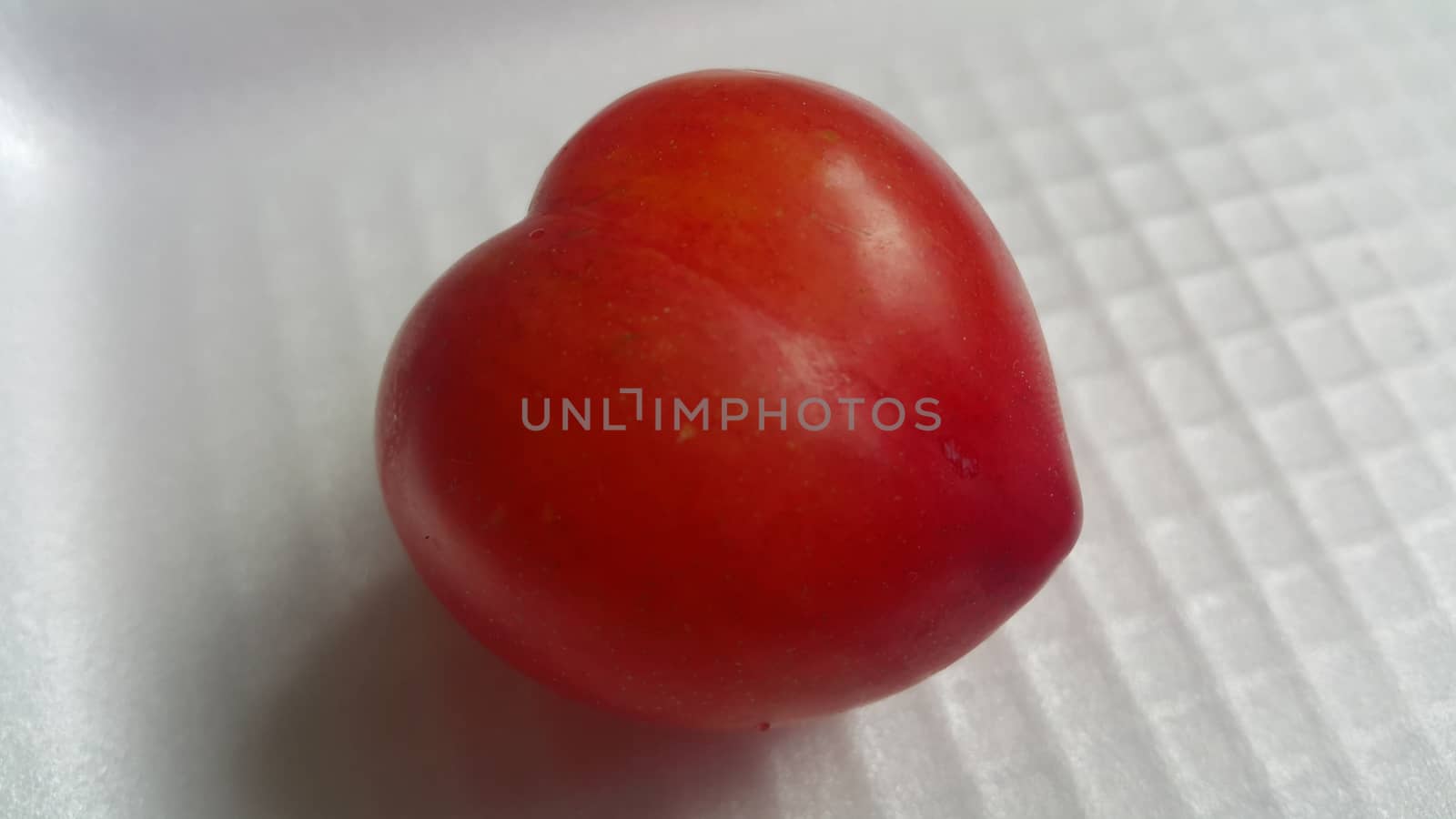 Closeup view of red plum on a white grey background by Photochowk