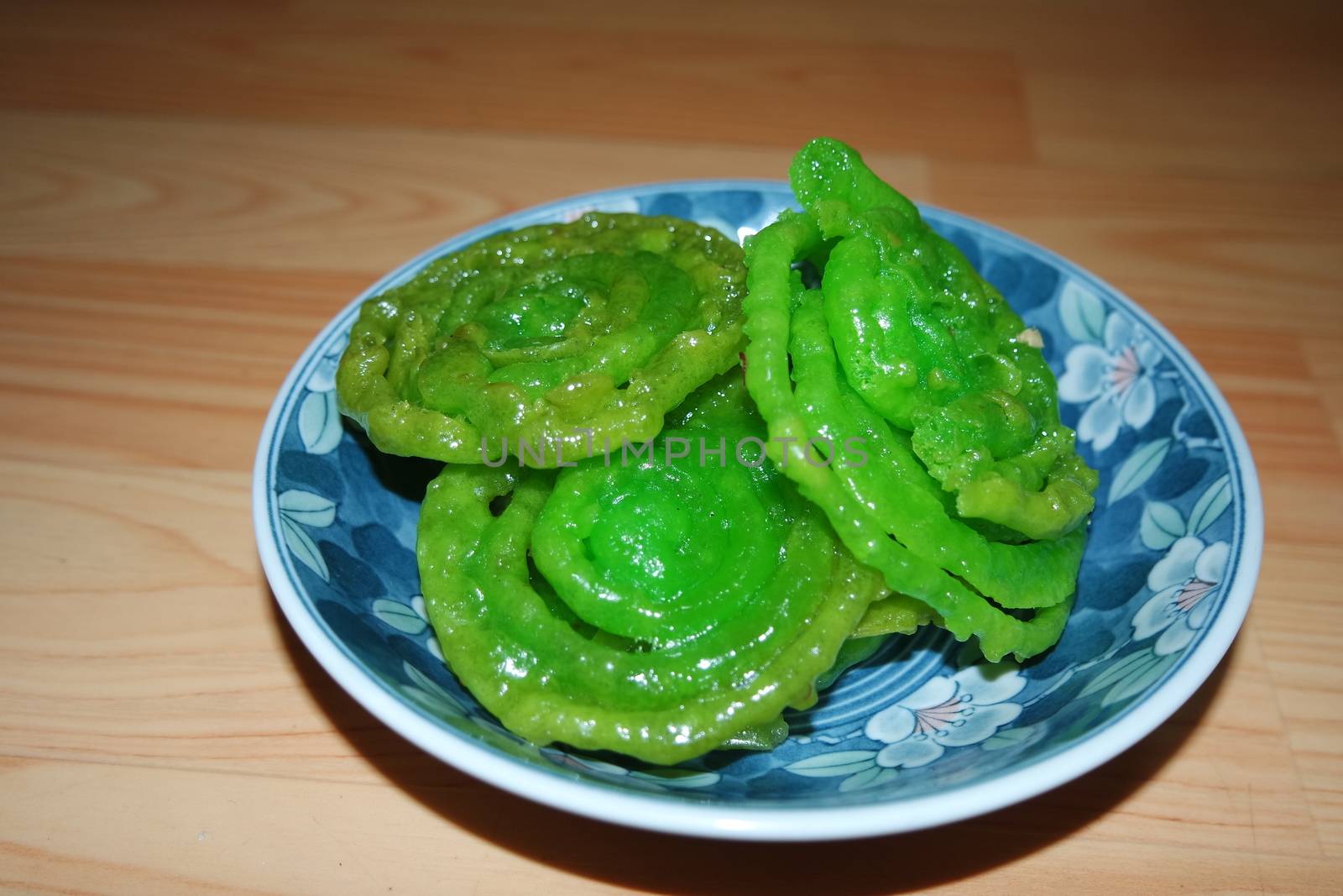 Crispy sweet Asian dessert green Jalebi cooked and served in ceramic plate. by Photochowk