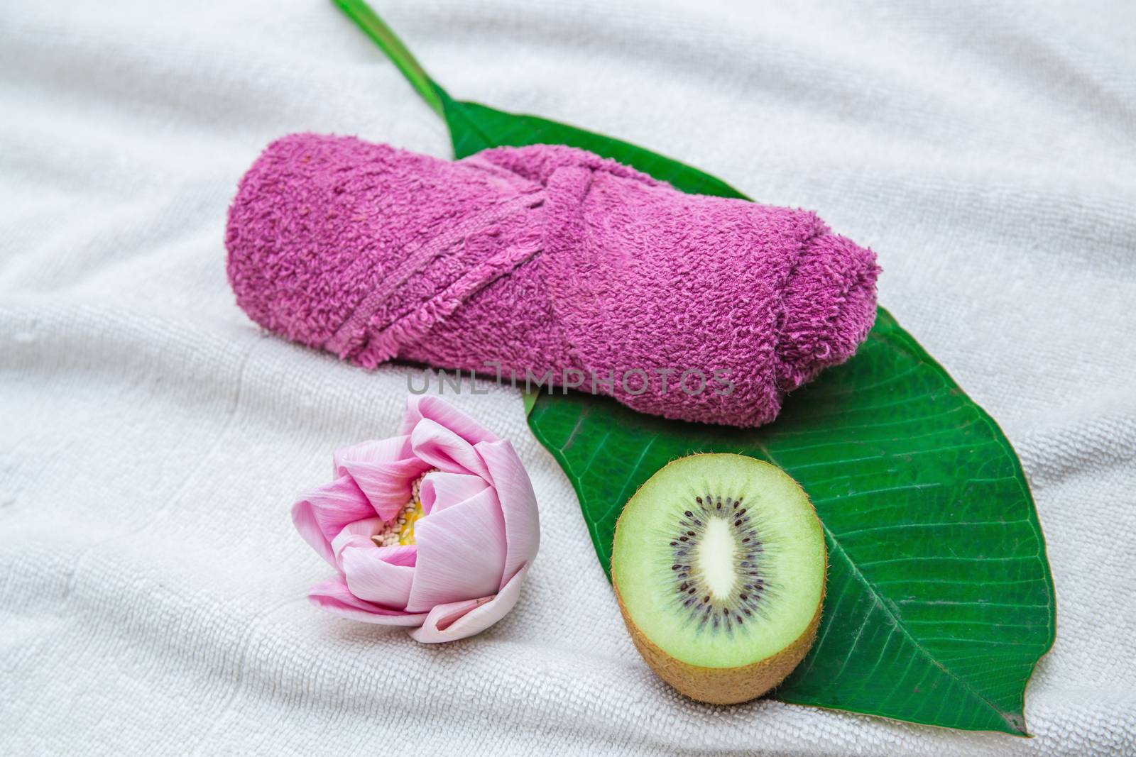 Rolled purple towel and flower with leaf