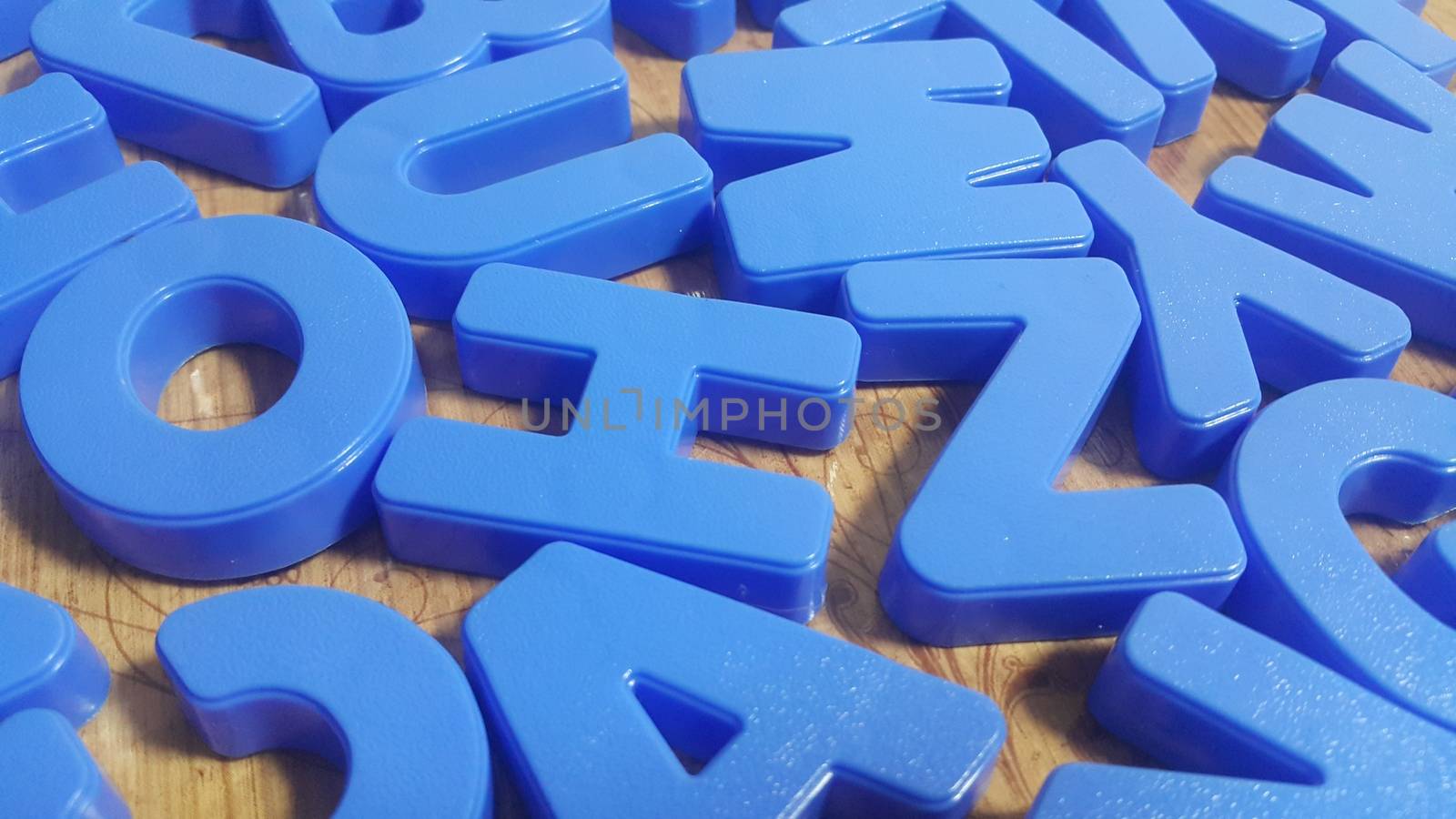 Set of plastic alphabet letters placed on a wooden floor by Photochowk