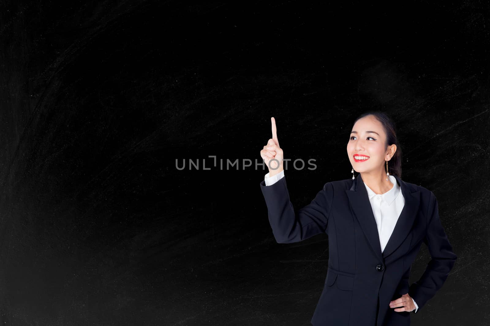 Happy young business woman pointing to empty chalkboar