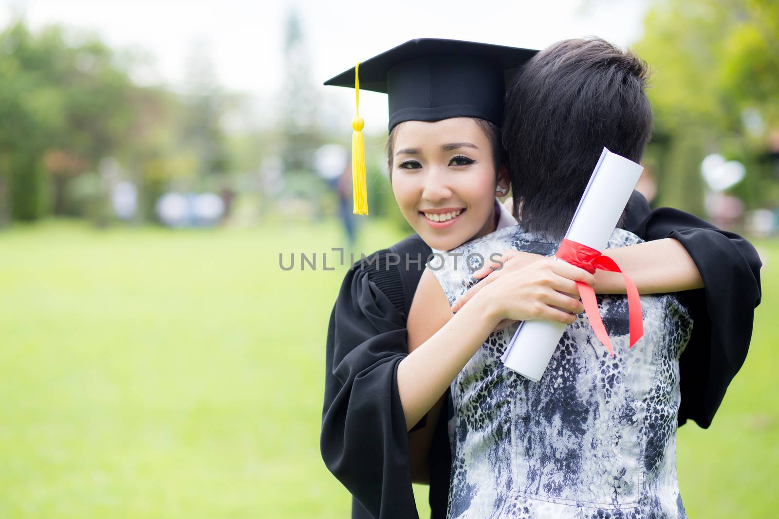 young female graduate hugging her friend at graduation ceremony