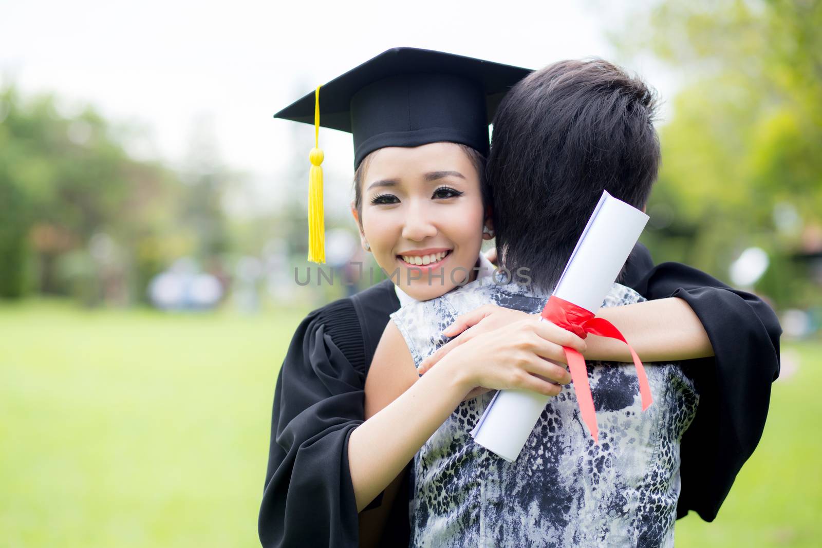 young female graduate hugging her friend at graduation ceremony