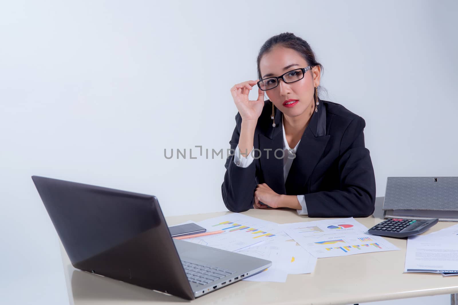 Businesswoman sitting at desk in office. He looks at the camera and smiling.